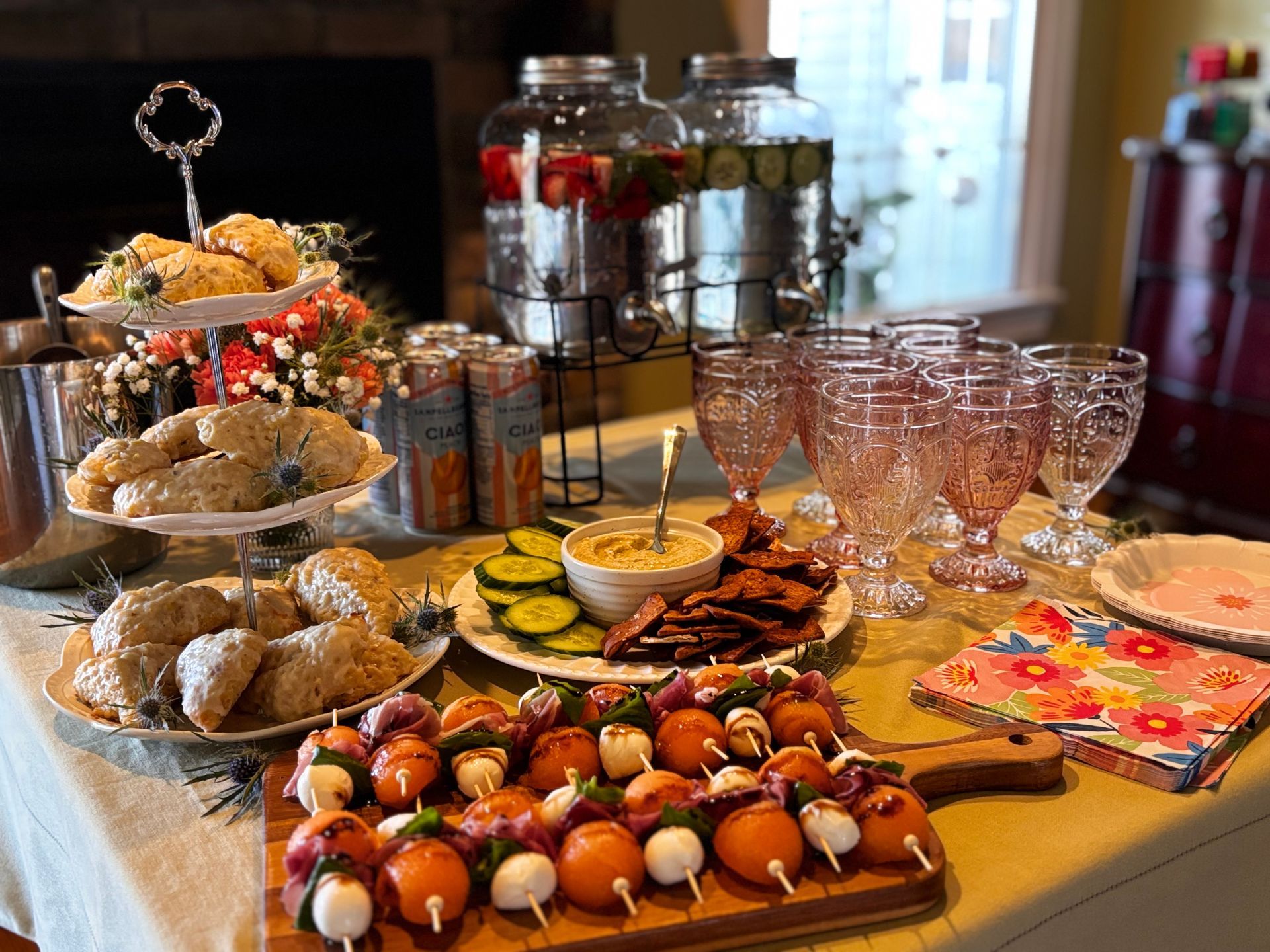 Charcuterie bowl with prosciutto, cheese, crackers, grapes, and almonds on a neutral background.
