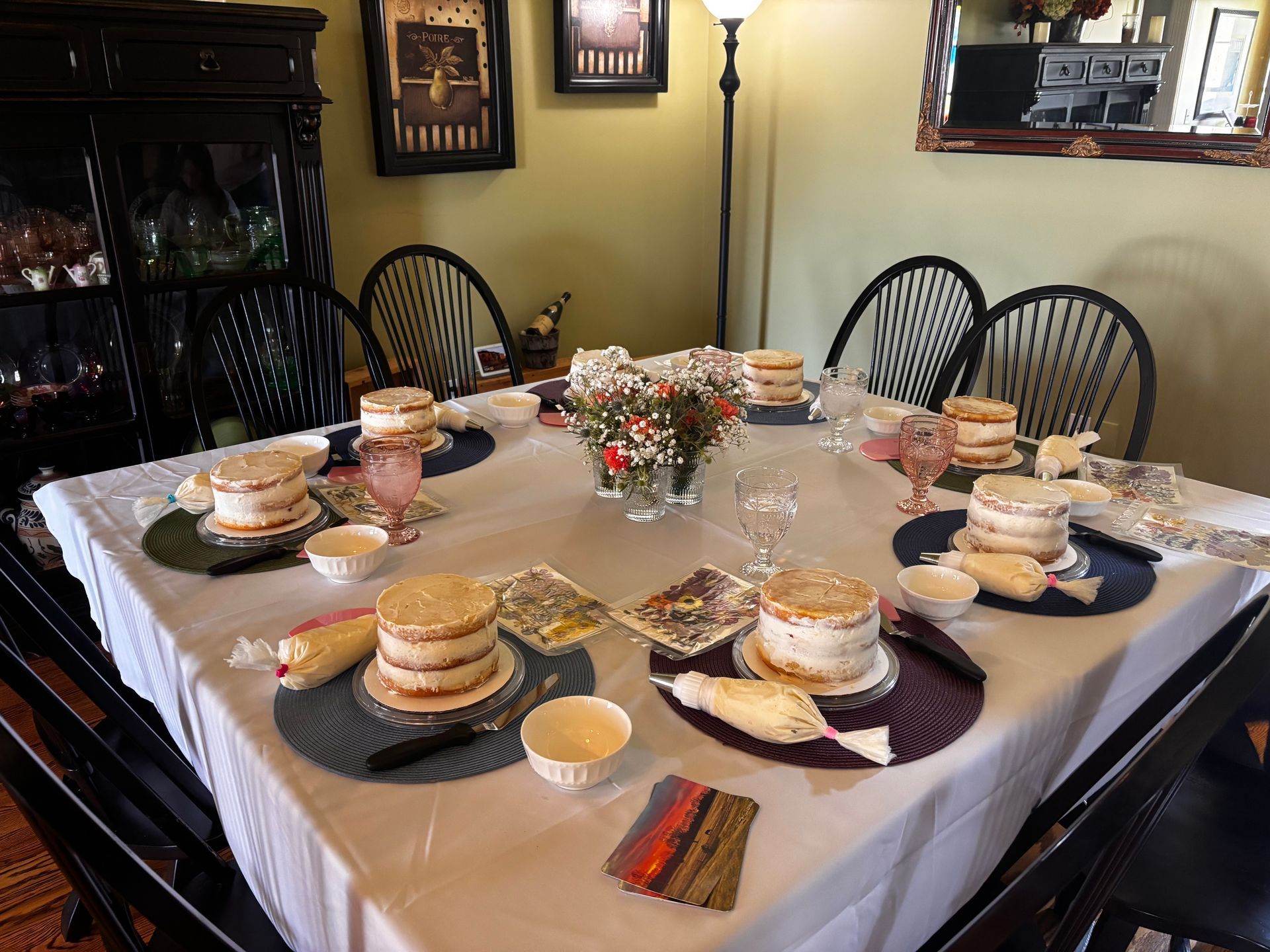People decorating cakes with frosting bags in a bright kitchen.