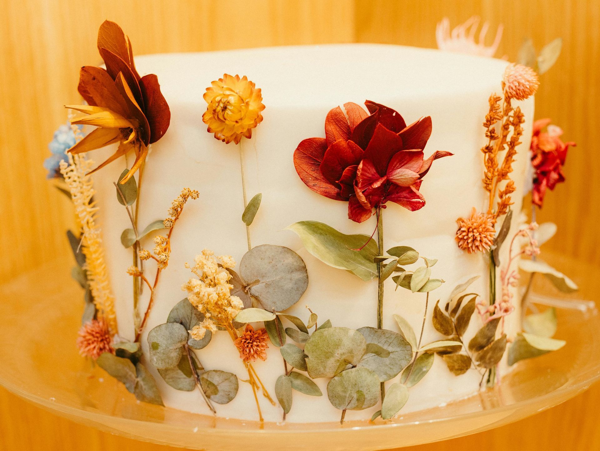 White cake decorated with colorful dried flowers.