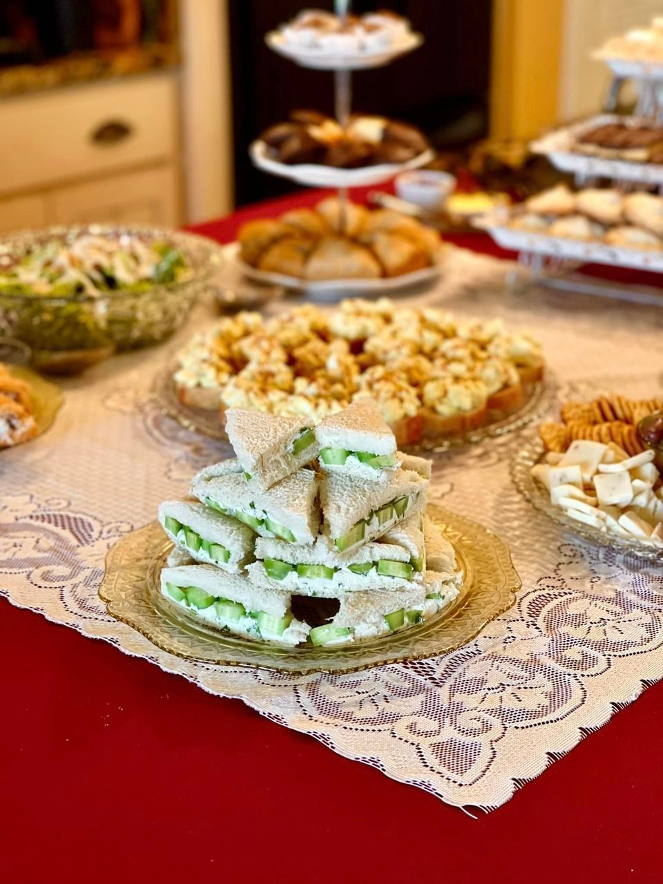 A table set for tea with sandwiches, pastries, and other treats on display.