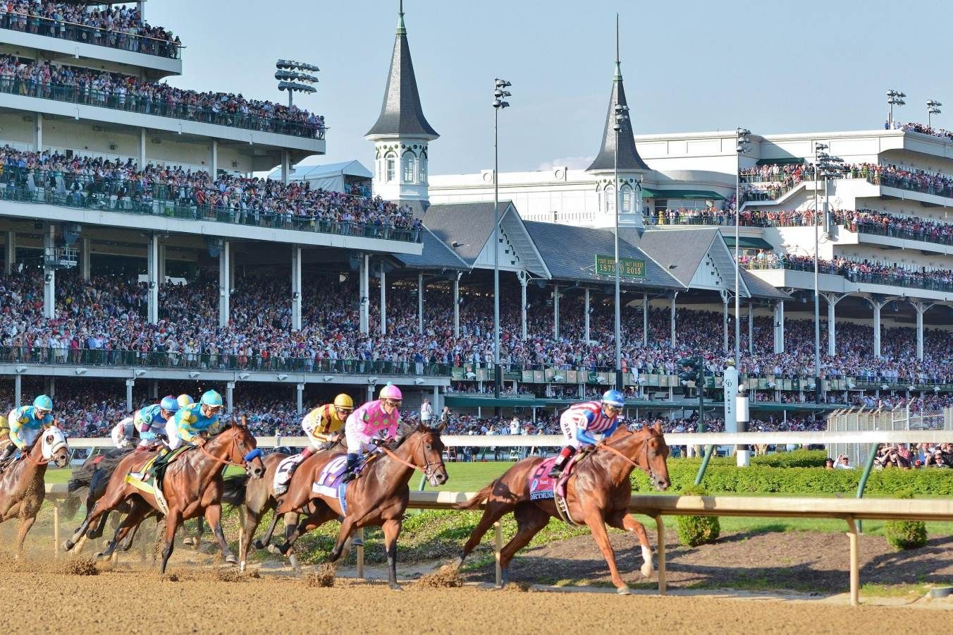A group of horses are racing on a race track.