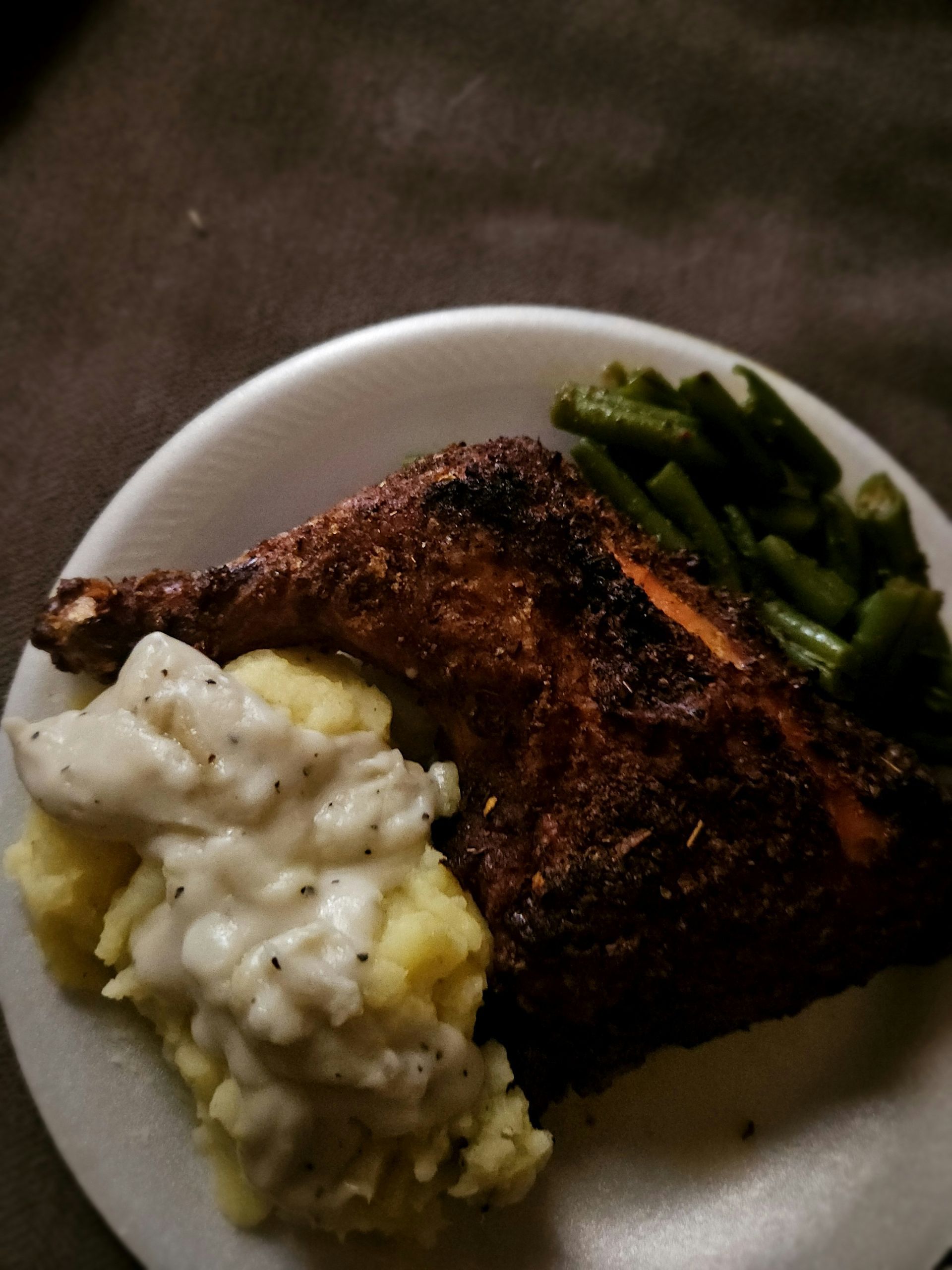 Plate of food: roasted chicken leg, mashed potatoes with gravy, and green beans.