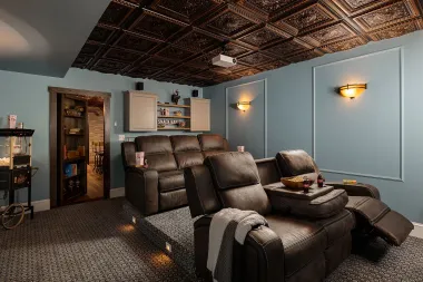 A home theater with a couch , chairs , and a projector.