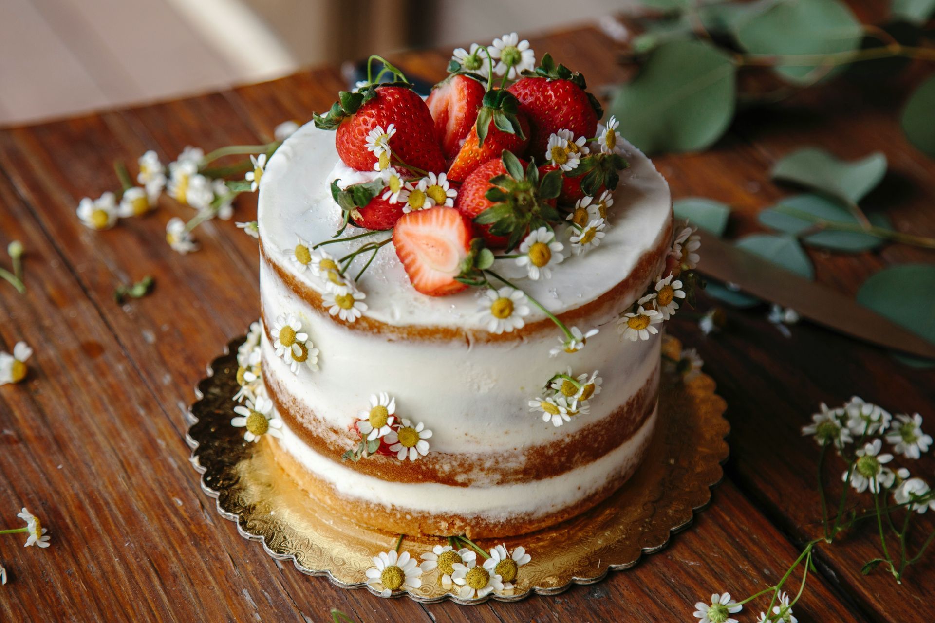 Cake decorated with flowers on a clear plate, against a warm, light background.