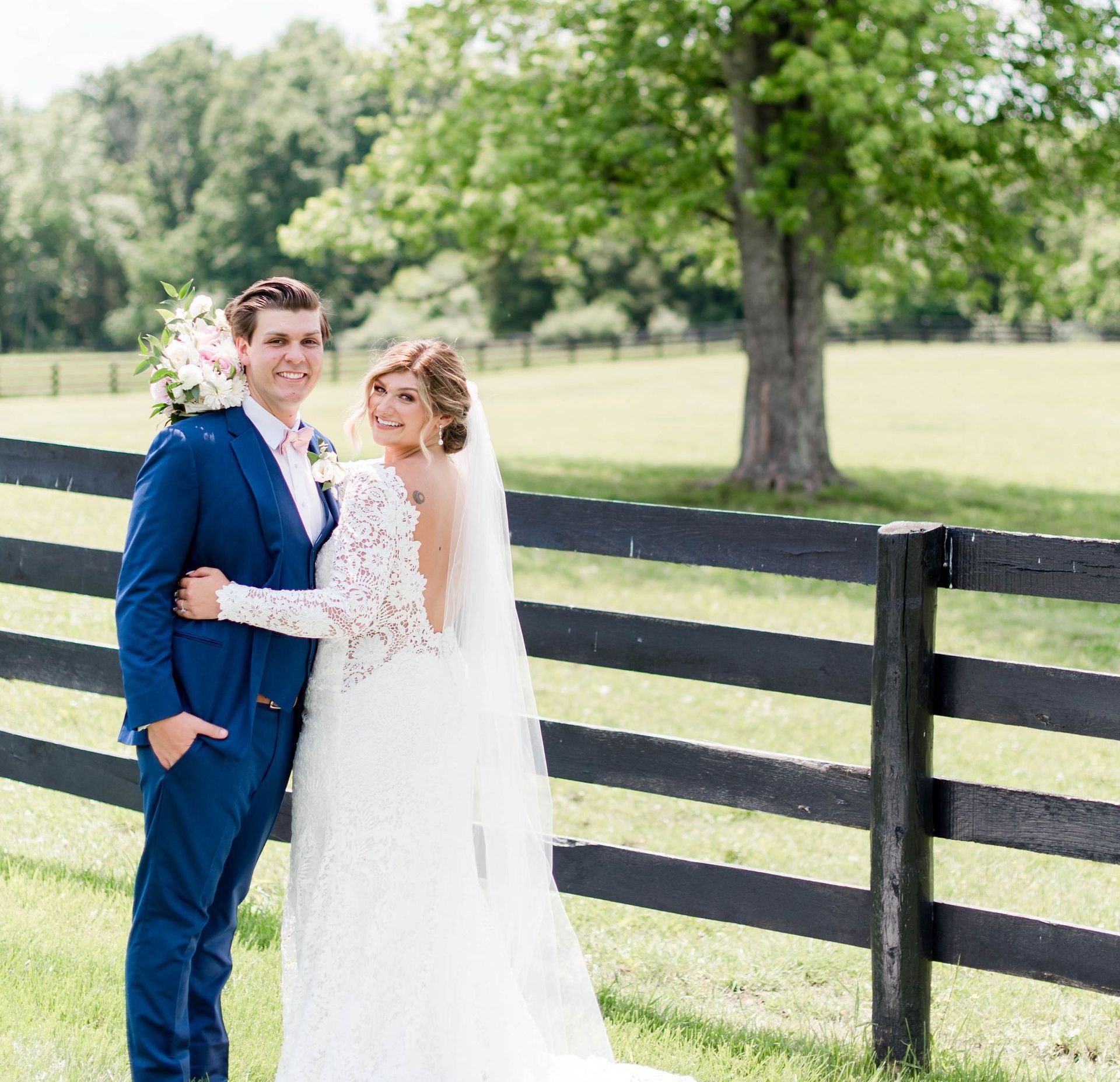 A bride and groom are posing for a picture in front of a black fence.