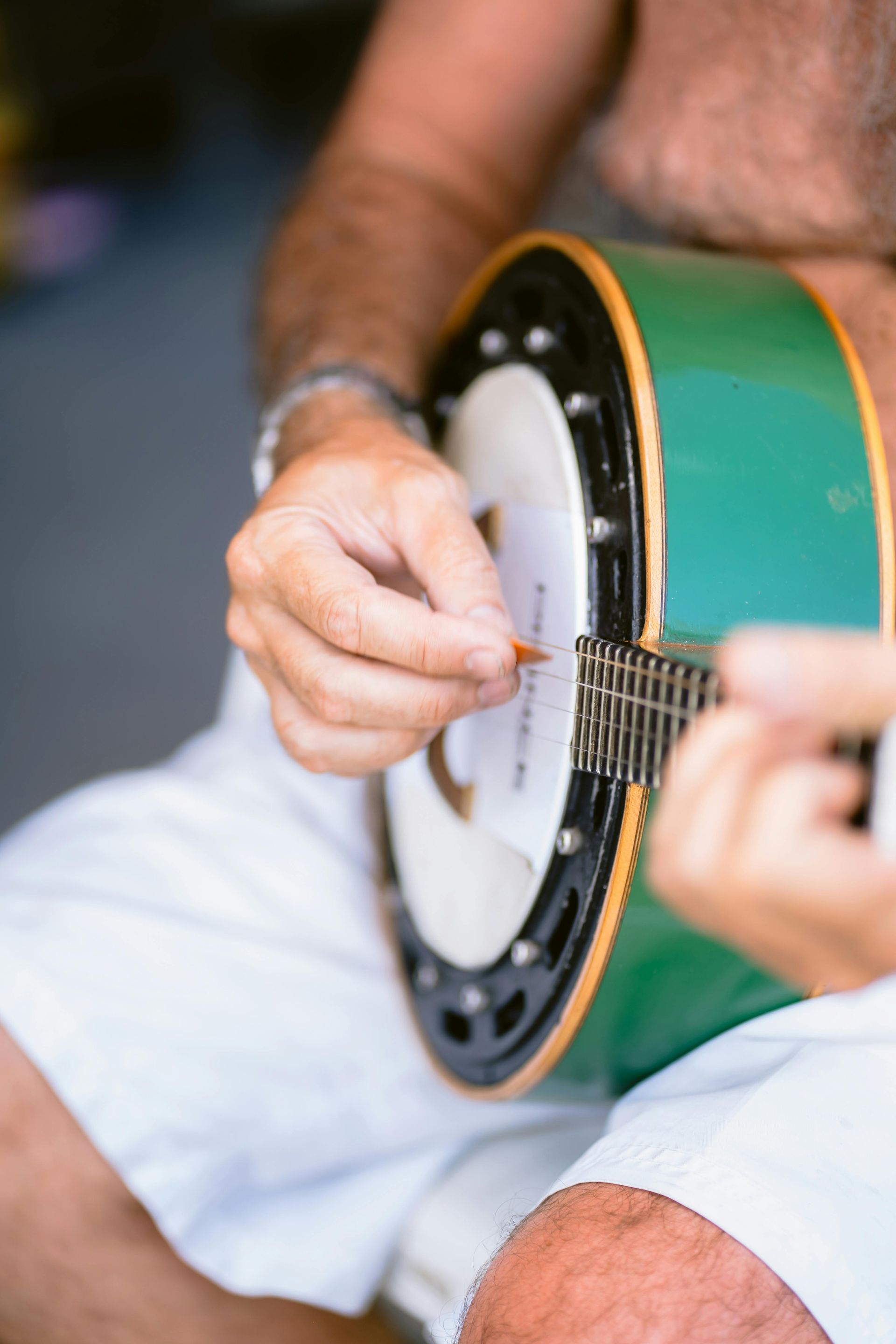 A man in white shorts is playing a green banjo