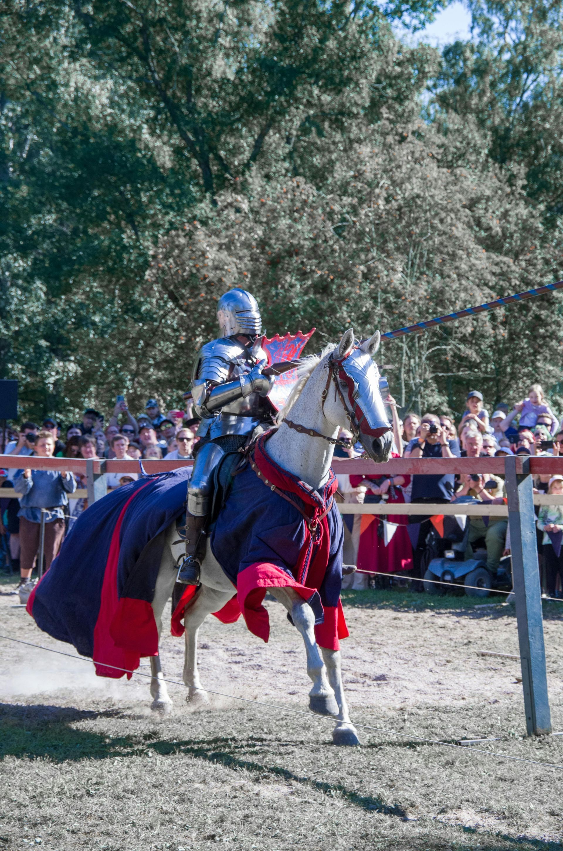 A man in armor is riding on the back of a horse.