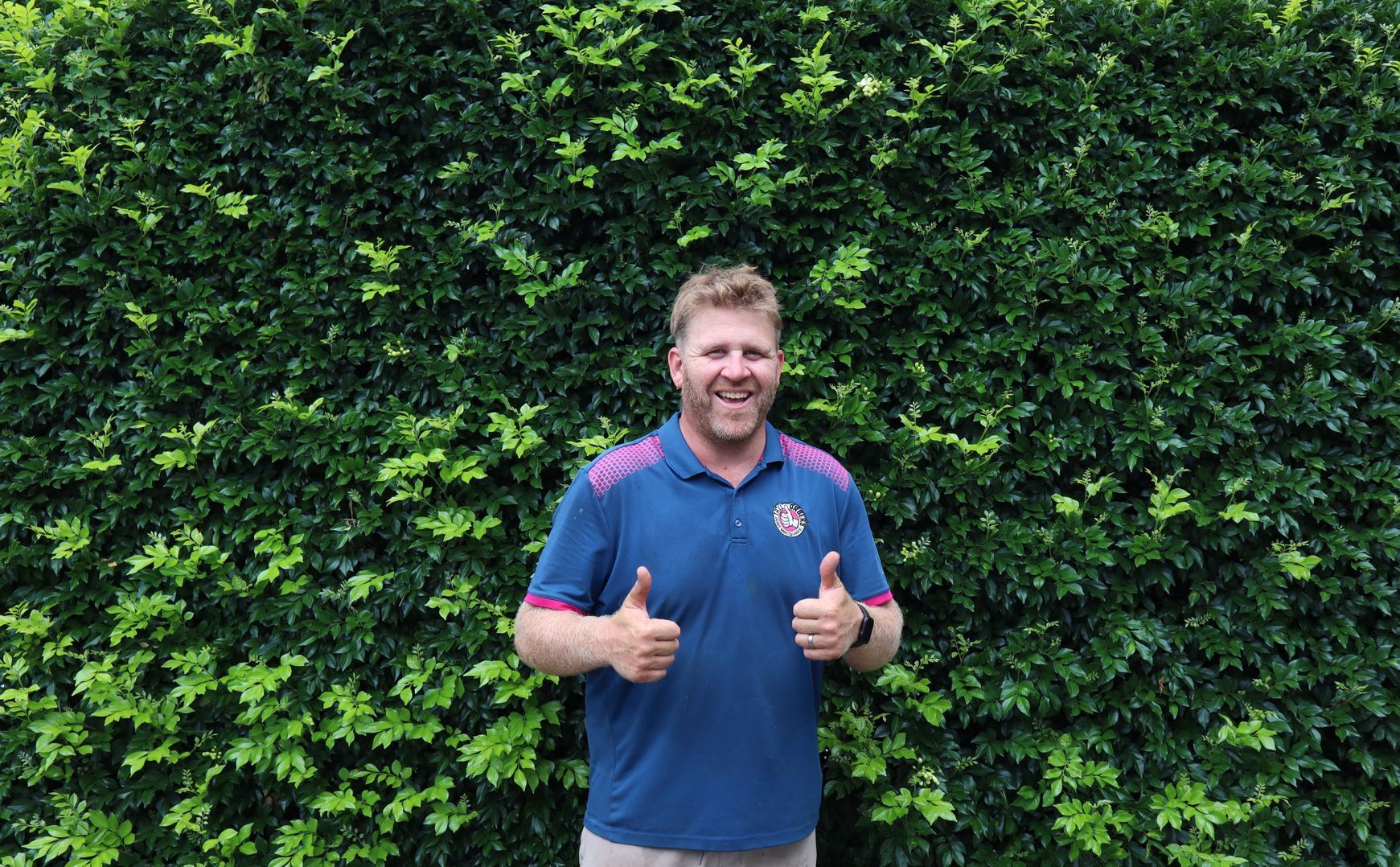 A Man Is Standing Next To A Tree In A Yard — Tall Orders Port Macquarie In Port Macquarie, NSW 