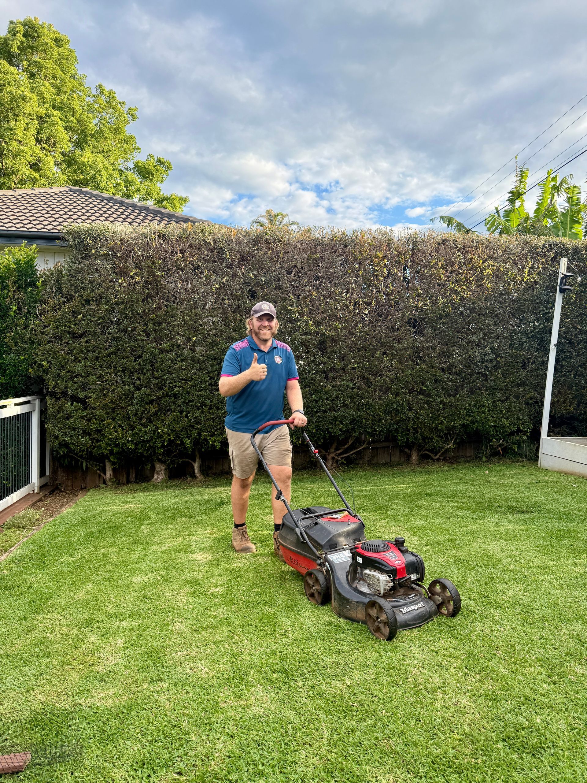 A Person Is Mowing A Lush Green Lawn With A Lawn Mower — Tall Orders Port Macquarie In Port Macquarie, NSW 