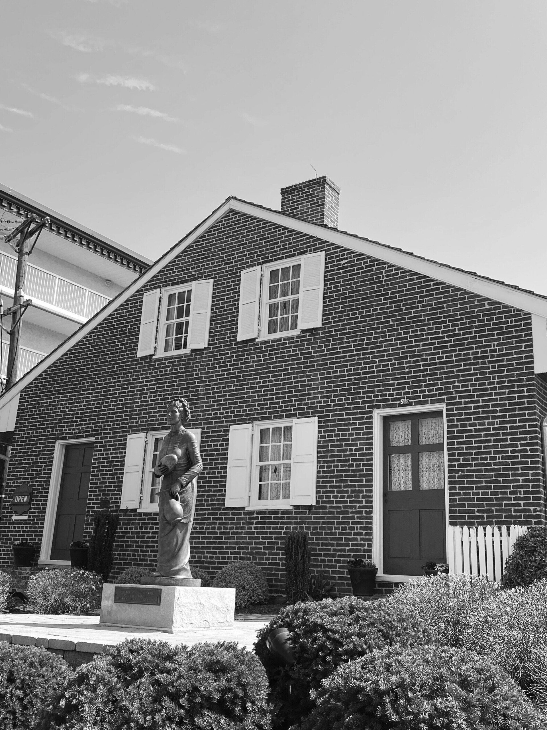 a black and white photo of a brick house with a statue in front of it