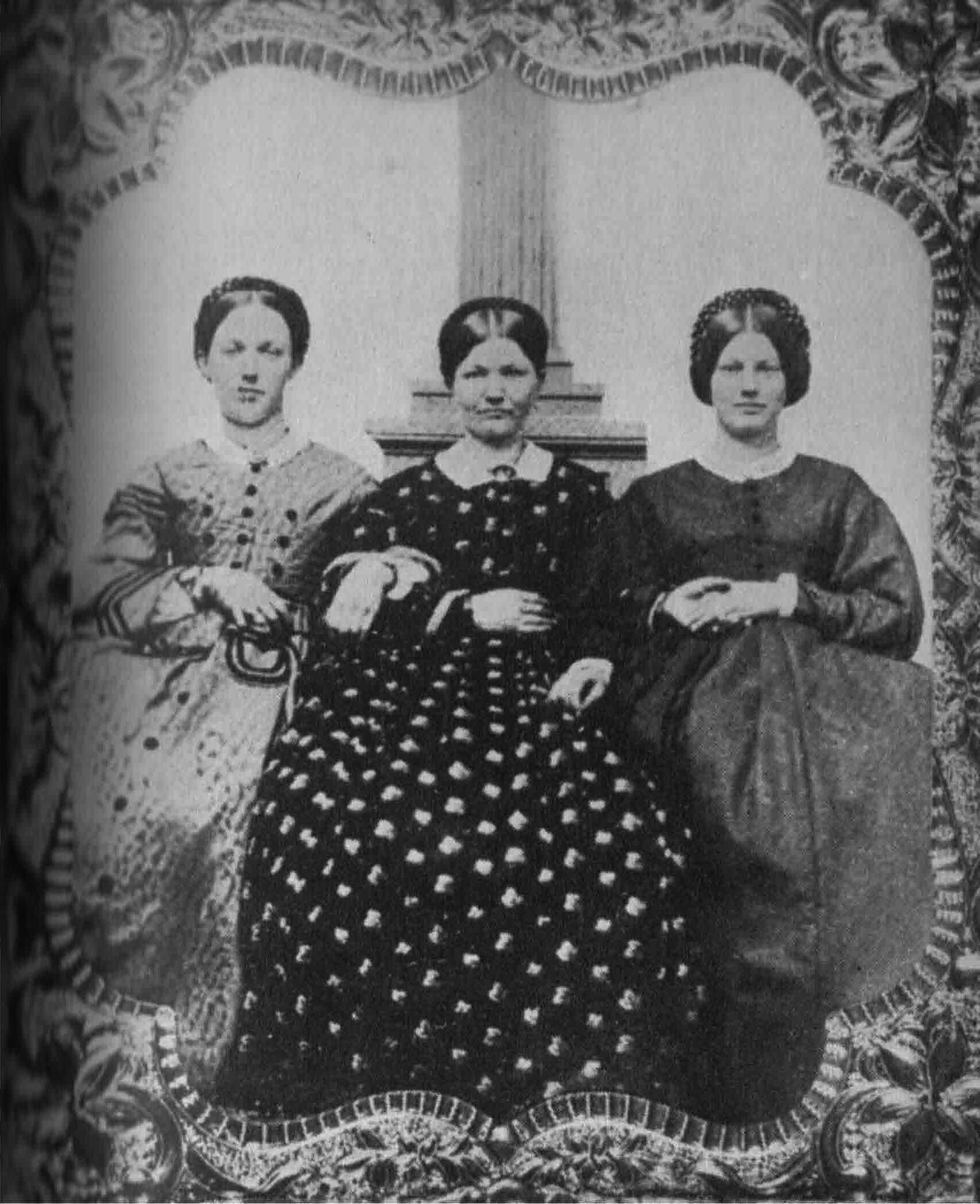 three women are posing for a picture in a black and white photo .