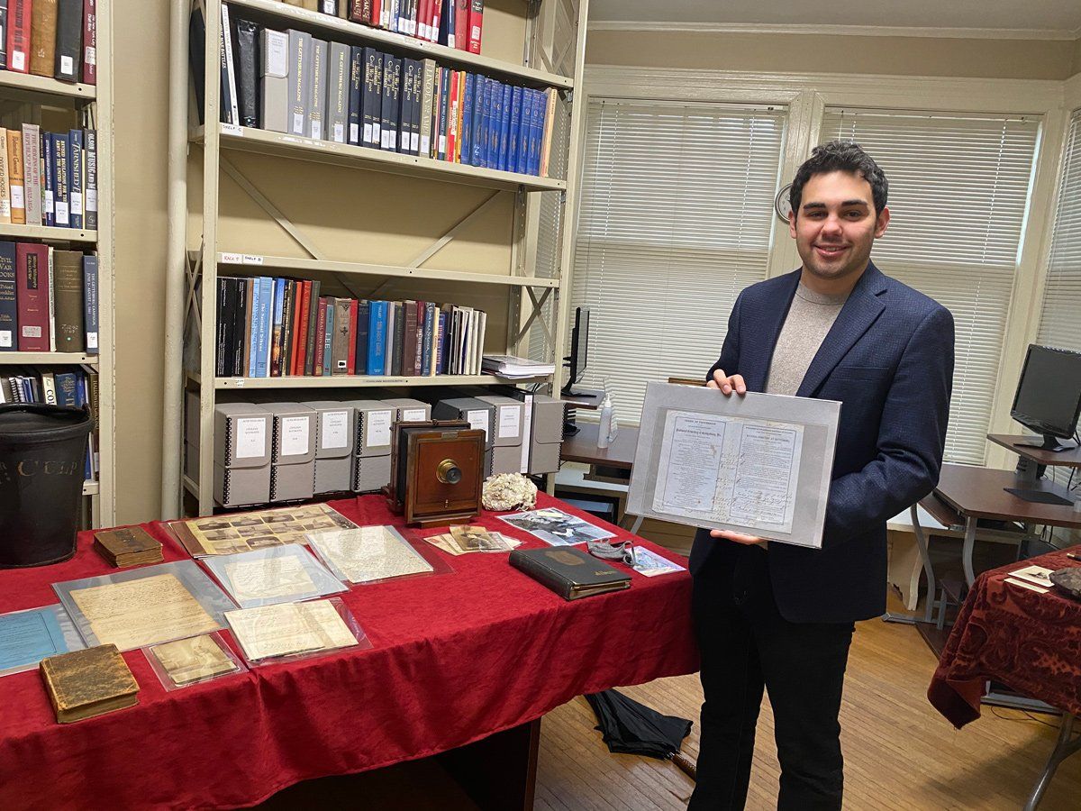 a man in a suit is holding a piece of paper in a library .
