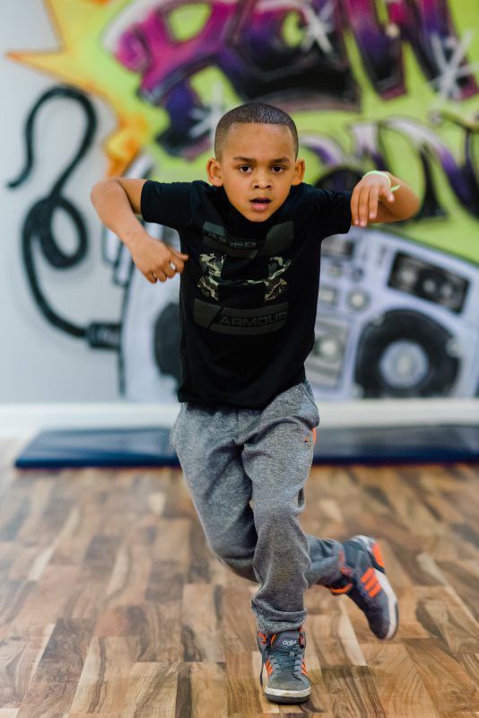 A young boy is dancing in a dance studio.