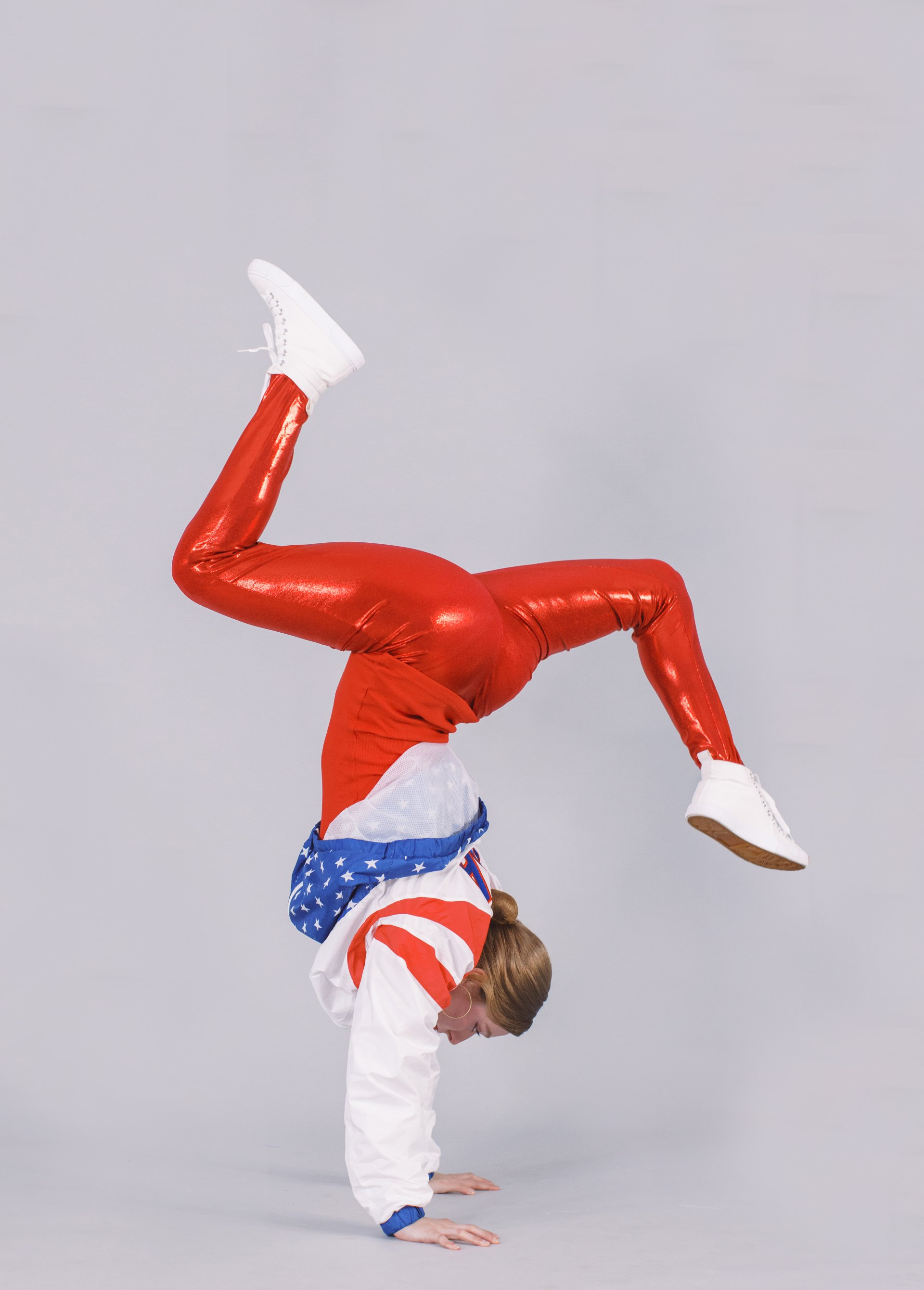 A woman is doing a handstand in a red , white and blue outfit.