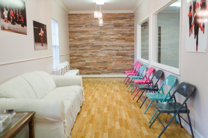 A waiting room with a couch , chairs and a mirror.
