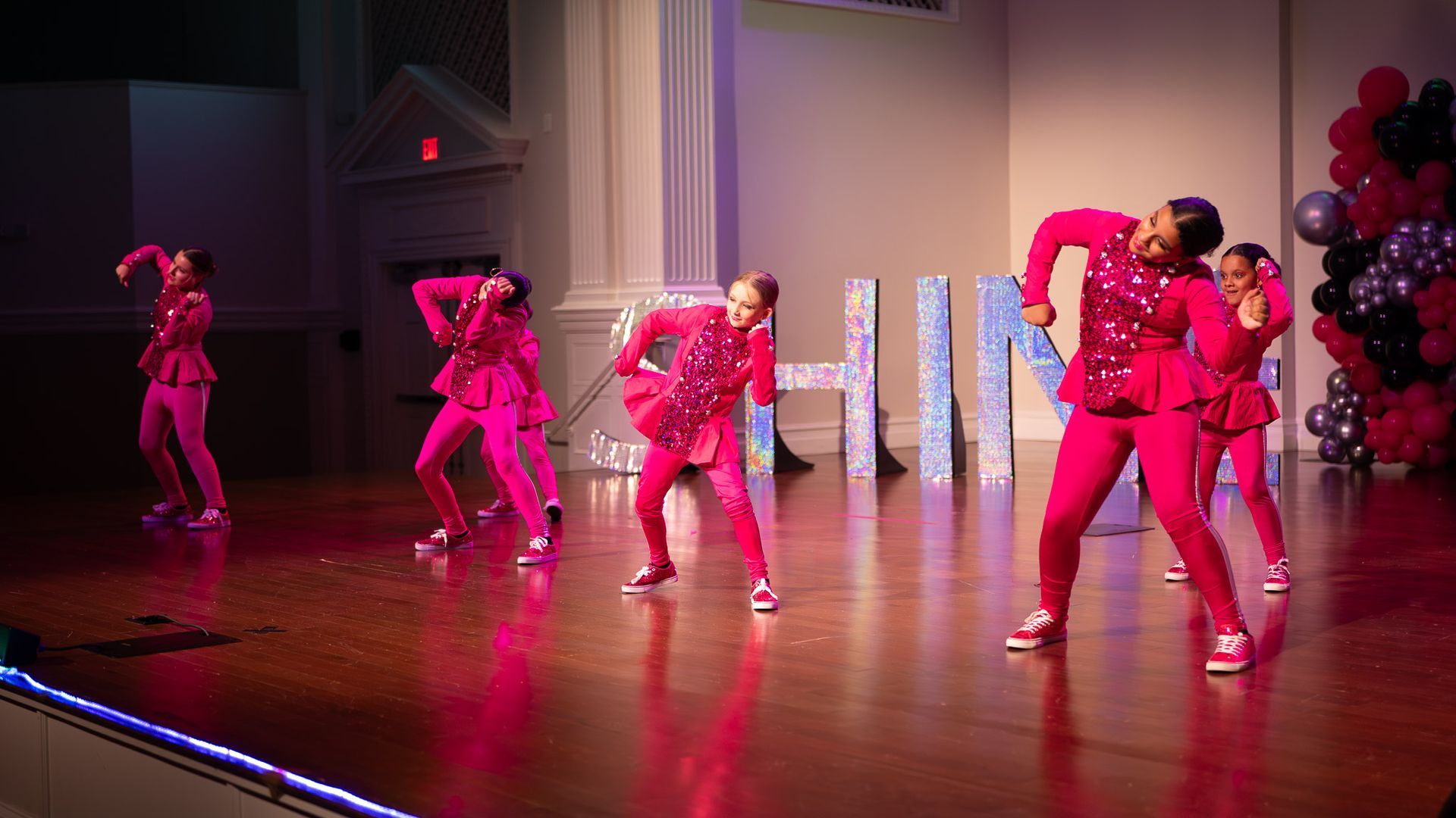 A woman in a pink shirt and blue striped pants is dancing.