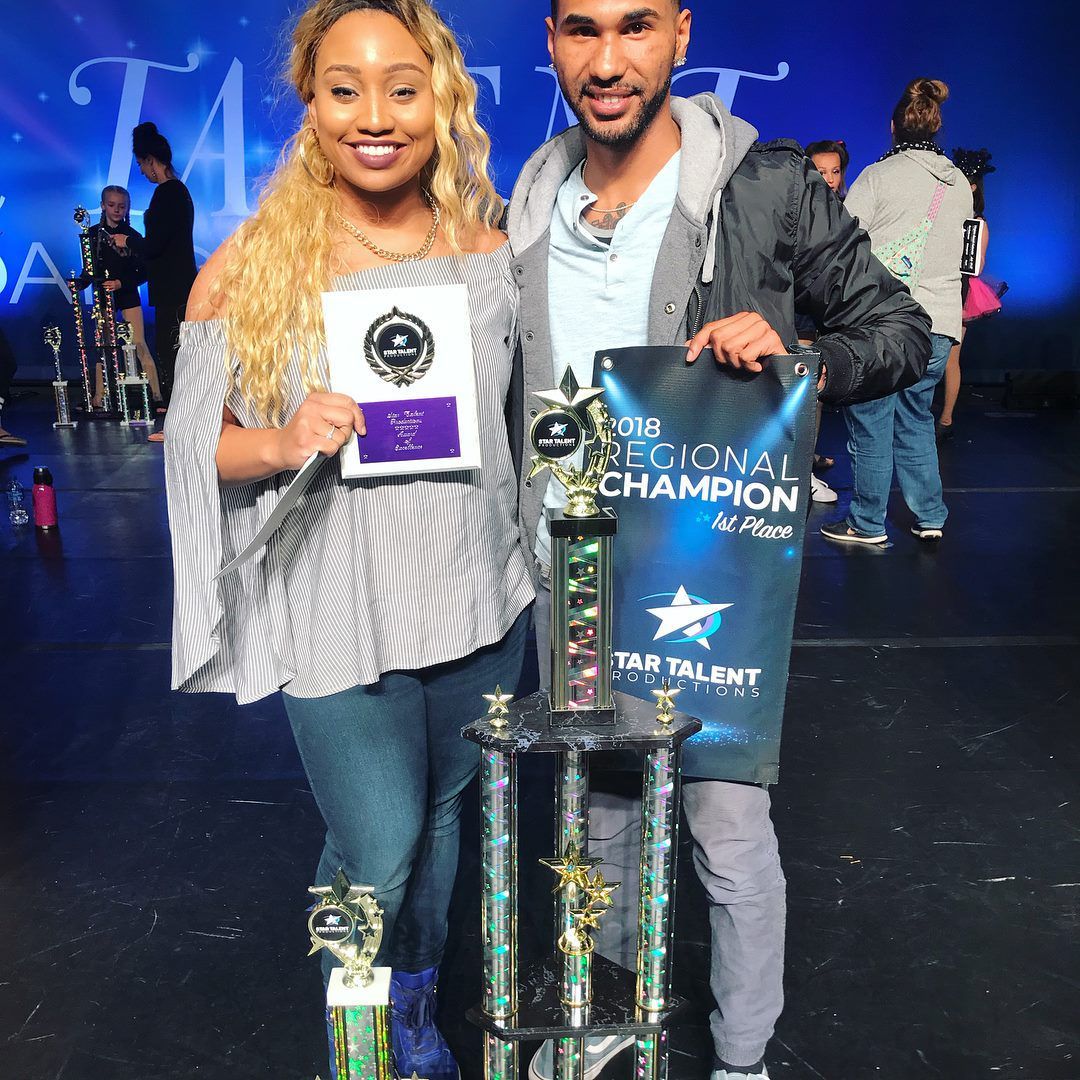 A man and a woman are standing next to each other holding trophies.