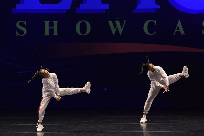 Three young girls in black and pink costumes are dancing