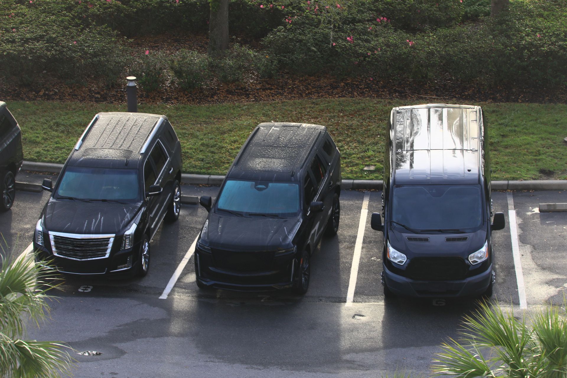 Three black cars are parked in a parking lot