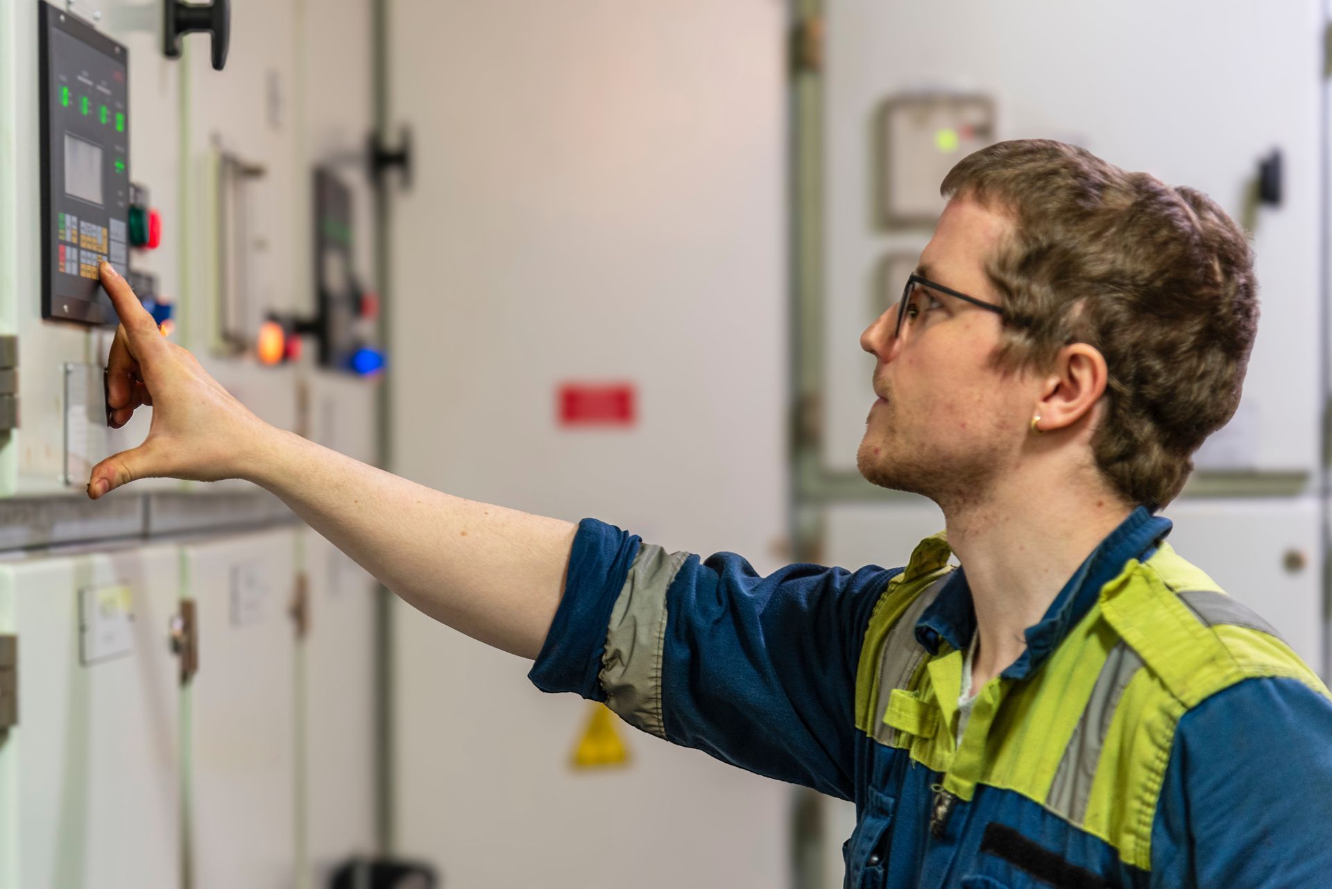 Technician operating a control panel while monitoring industrial equipment during emissions testing.