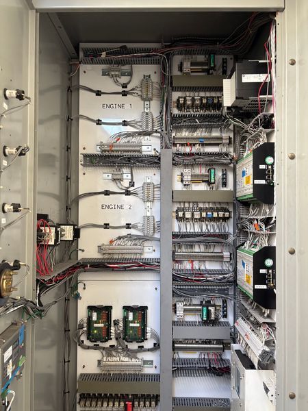 Electrical control panel with wires, relays, and circuit boards.