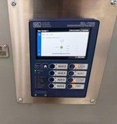 An SEL-7000 series protection relay mounted on a metal panel, displaying electrical system status on its screen.