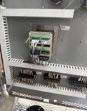Electrical control cabinet interior showing terminal blocks and wiring connections on a gray metal backplane.