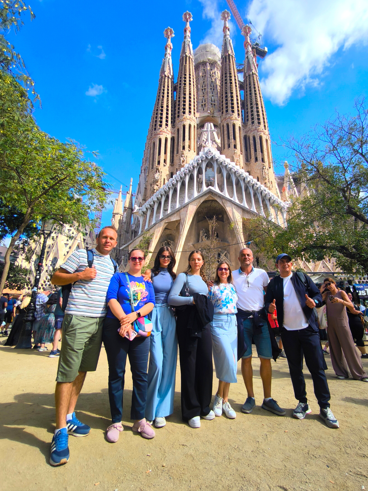 Grup de turiști în fața Sagrada Familia într-o zi însorită
