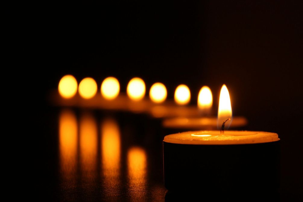 A row of lit candles in a dark room.