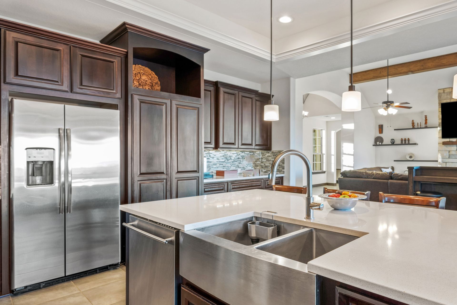 Modern kitchen with stainless steel appliances, dark wood cabinets, and white countertops.