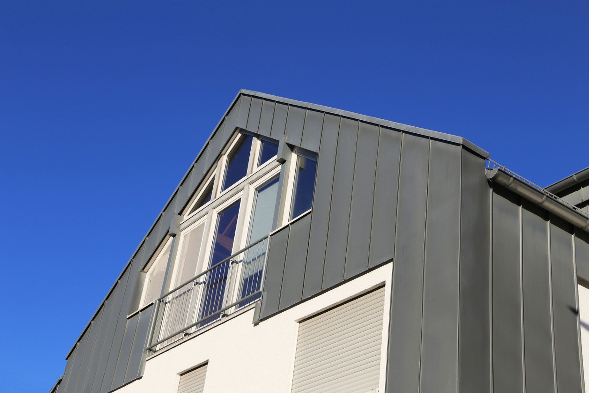 Gray Metal-clad Roof and White Building With Balcony Against a Clear Blue Sky — Your Craftsmen in Raymond Terrace, NSW