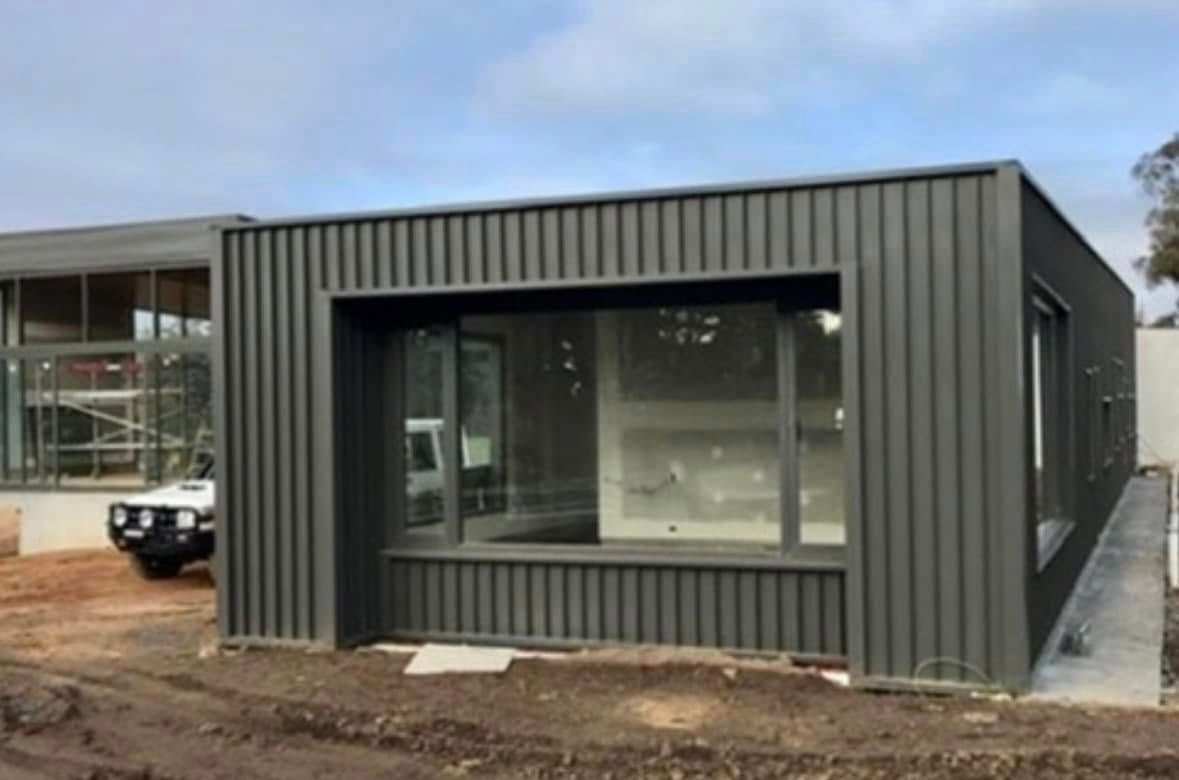 Dark Gray Modern Building With Large Windows Under a Cloudy Sky, Sitting on Dirt — Your Craftsmen in Eleebana, NSW