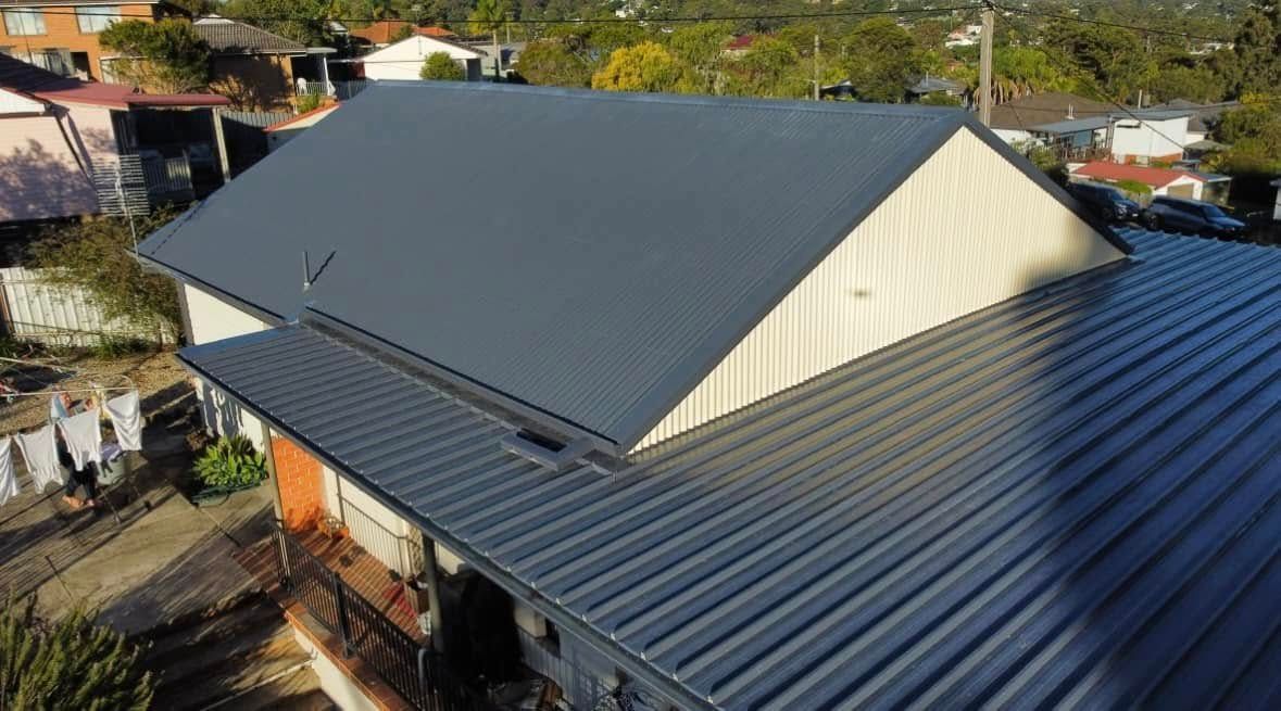 Dark gray corrugated metal roof on a house, angled view, sunny day. — Your Craftsmen in Eleebana, NSW