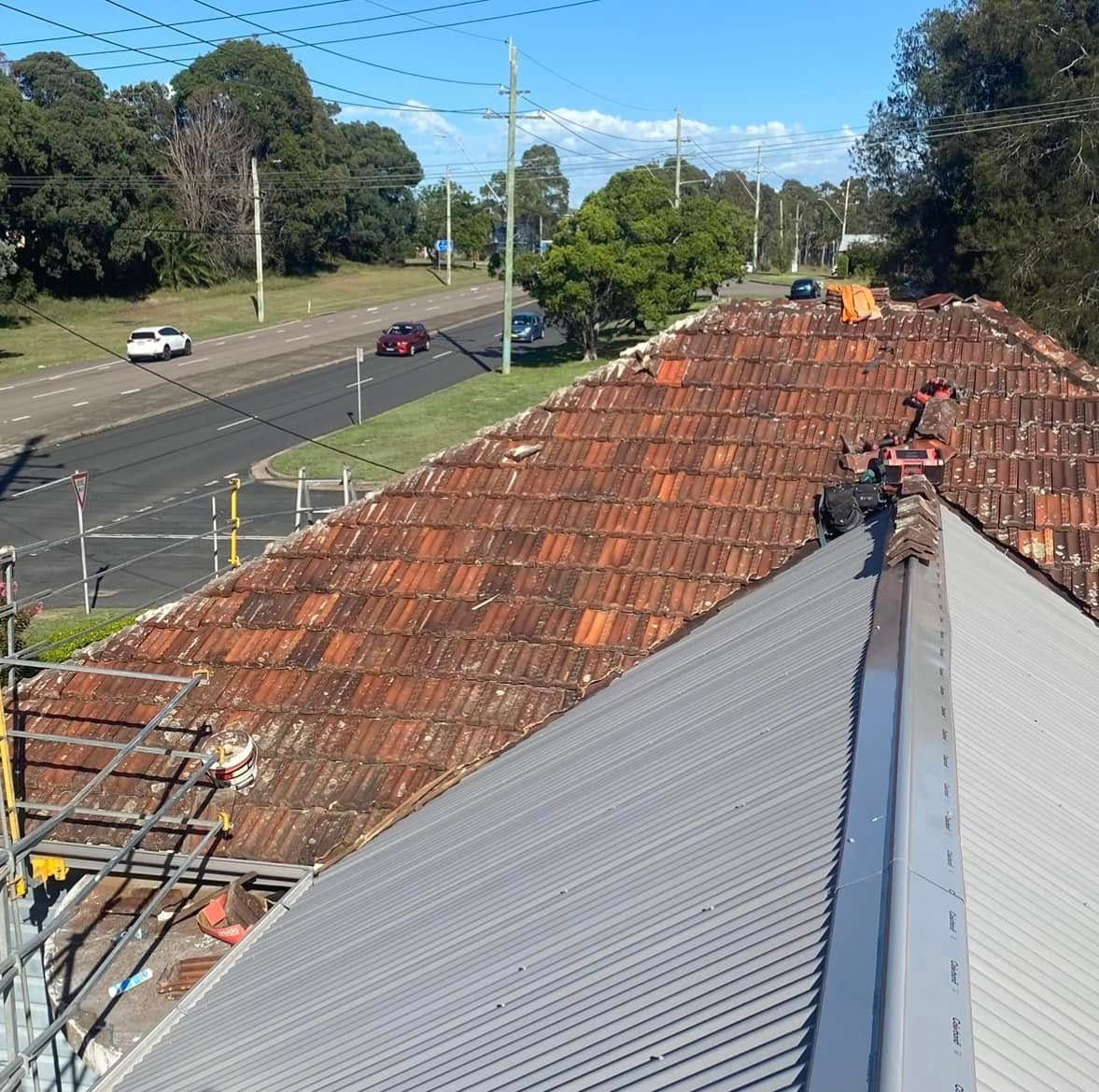a House Roof Under Construction, Featuring Old Orange Tiles and New Gray Metal Sheets — Your Craftsmen in Eleebana, NSW