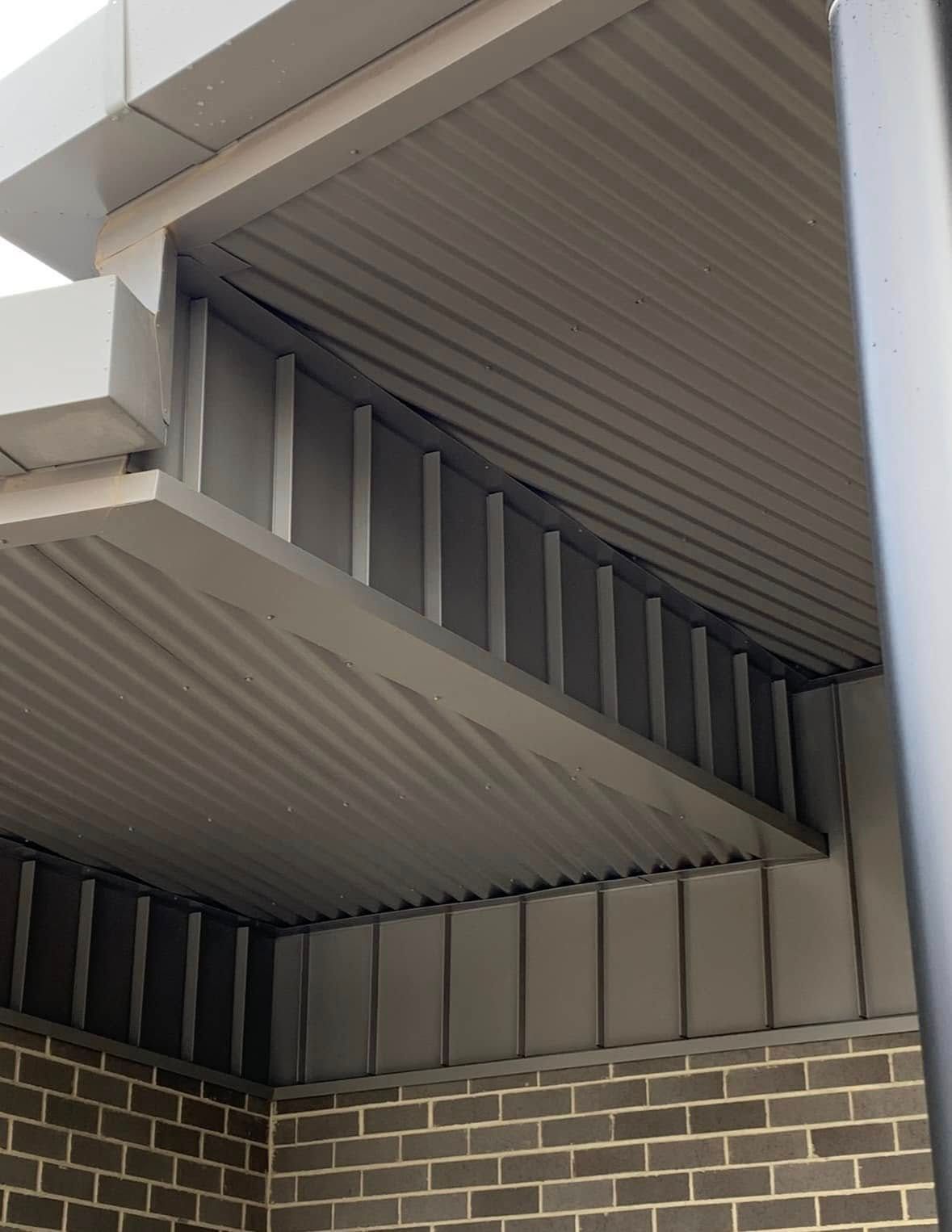 Gray Corrugated Metal Roof Over a Brick Building, With a Slanted Section — Your Craftsmen in Eleebana, NSW