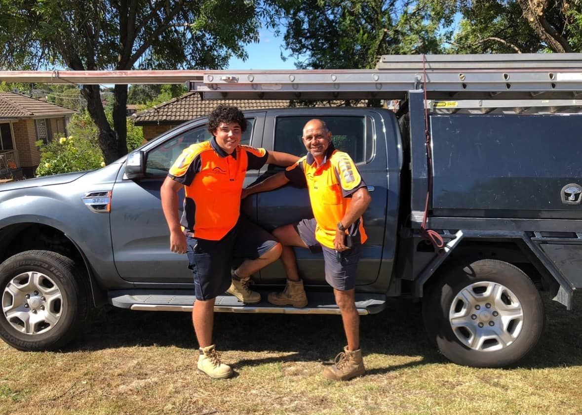 Two Men in Work Shirts Pose Beside a Truck With a Ladder Rack — Your Craftsmen in Eleebana, NSW