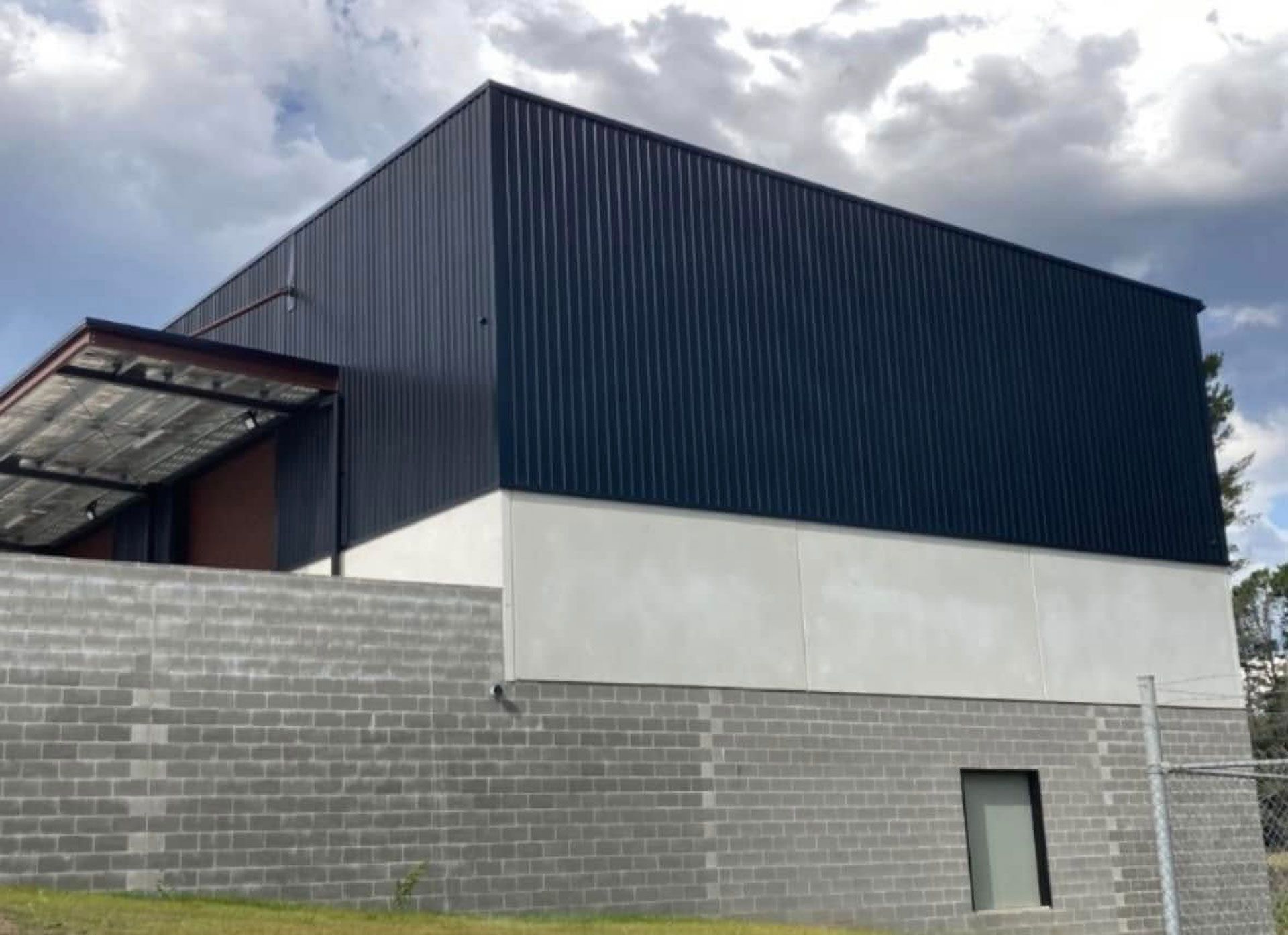Dark Blue Corrugated Metal Building With a White Base on a Cinder Block Foundation — Your Craftsmen in Merewether, NSW