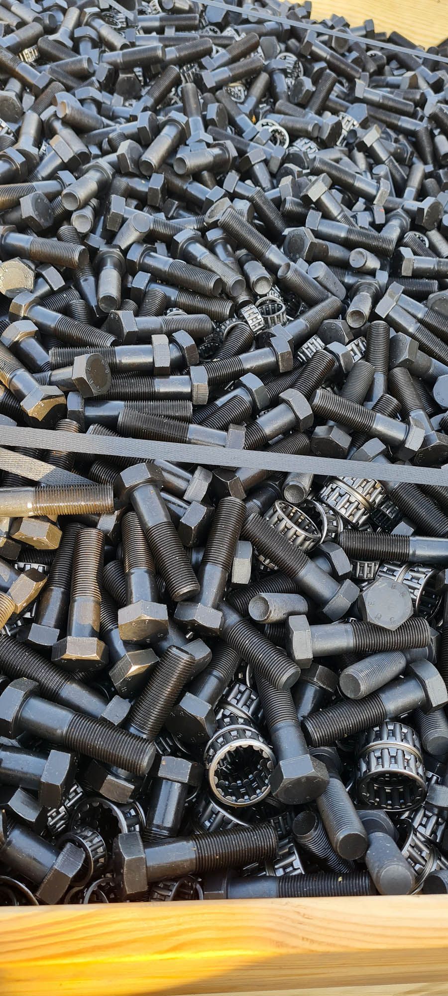 Un mucchio di dadi e bulloni neri in una scatola di legno.