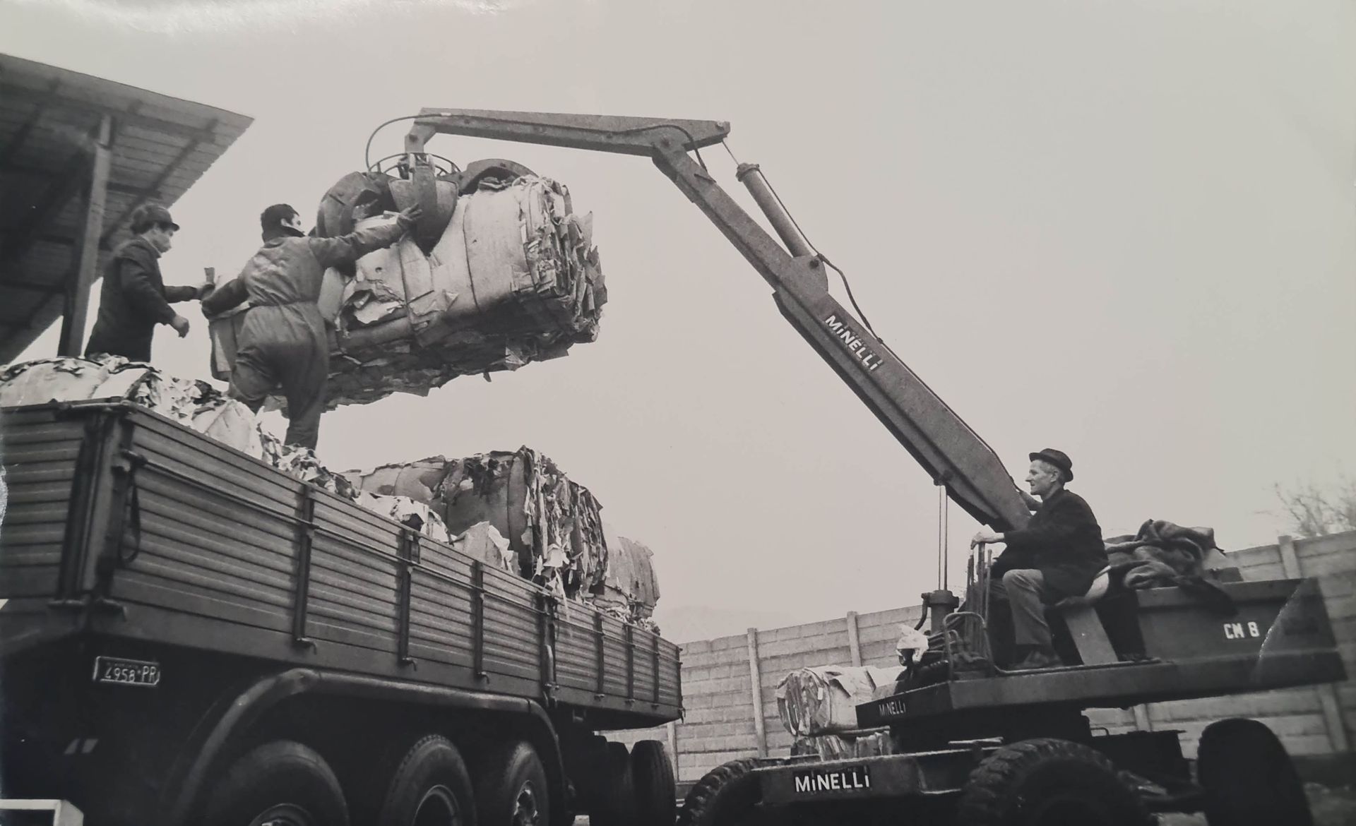 Una foto in bianco e nero di un camion sollevato da una gru