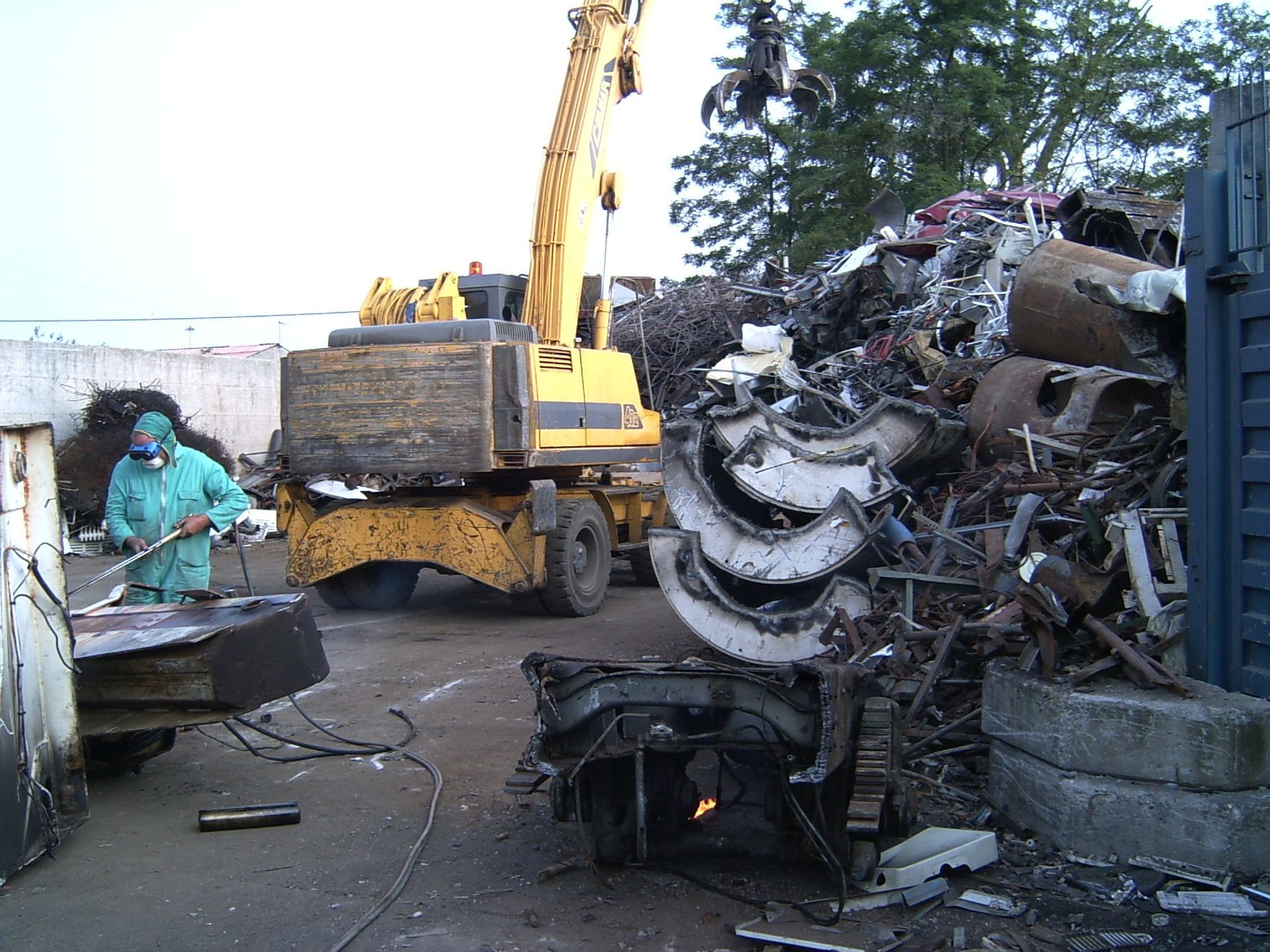 Un uomo che indossa una maschera è in piedi davanti a un mucchio di rottami metallici