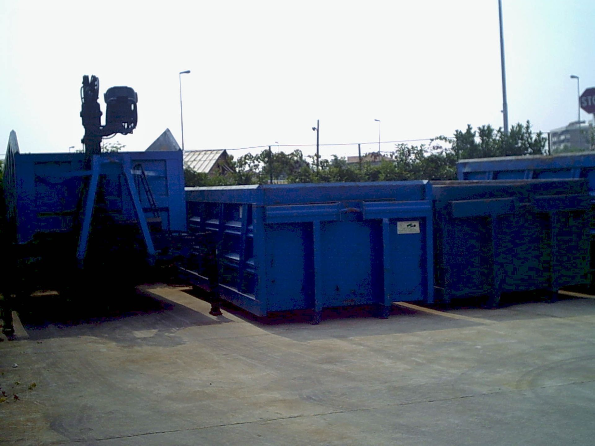 Due cassonetti blu sono parcheggiati uno accanto all'altro in un parcheggio.