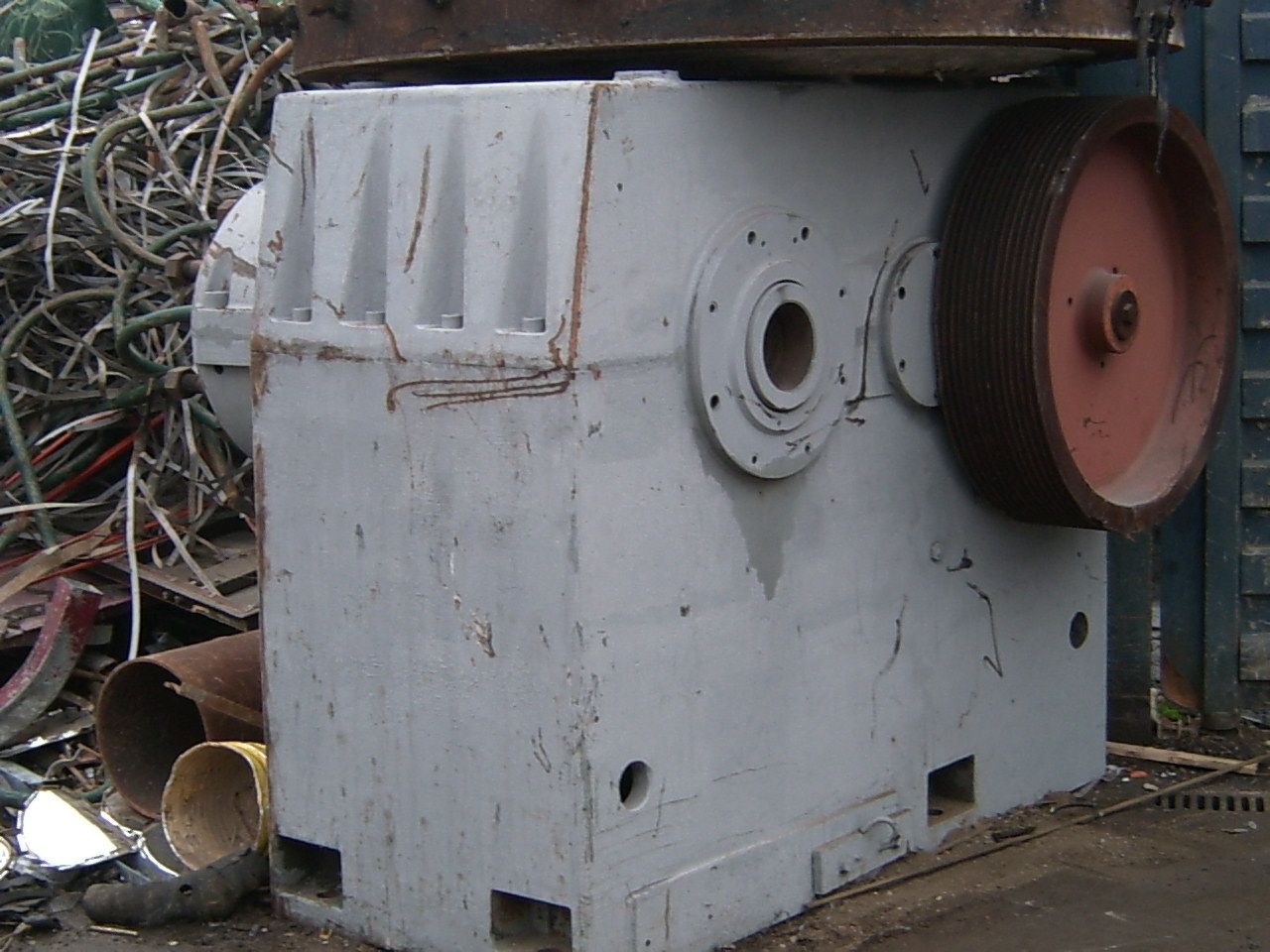 Una macchina con una ruota rossa è seduta davanti a un mucchio di rottami metallici