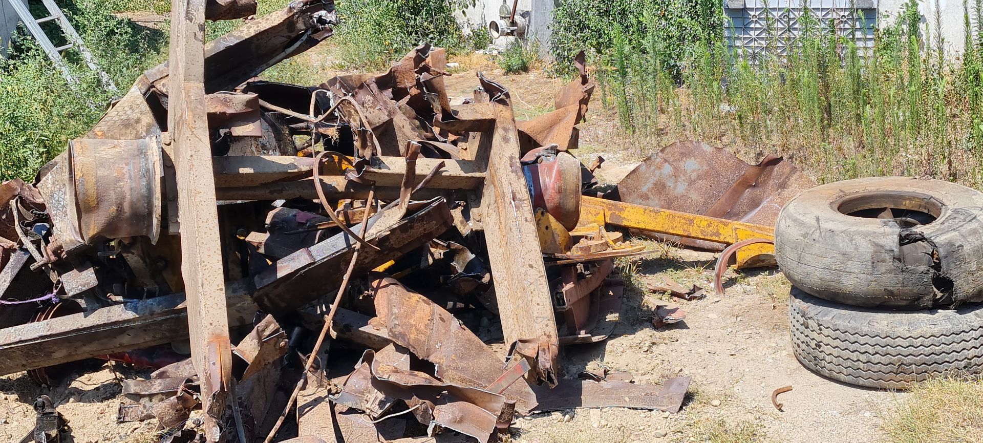 A terra accanto a una pila di pneumatici c'è un mucchio di metallo arrugginito.