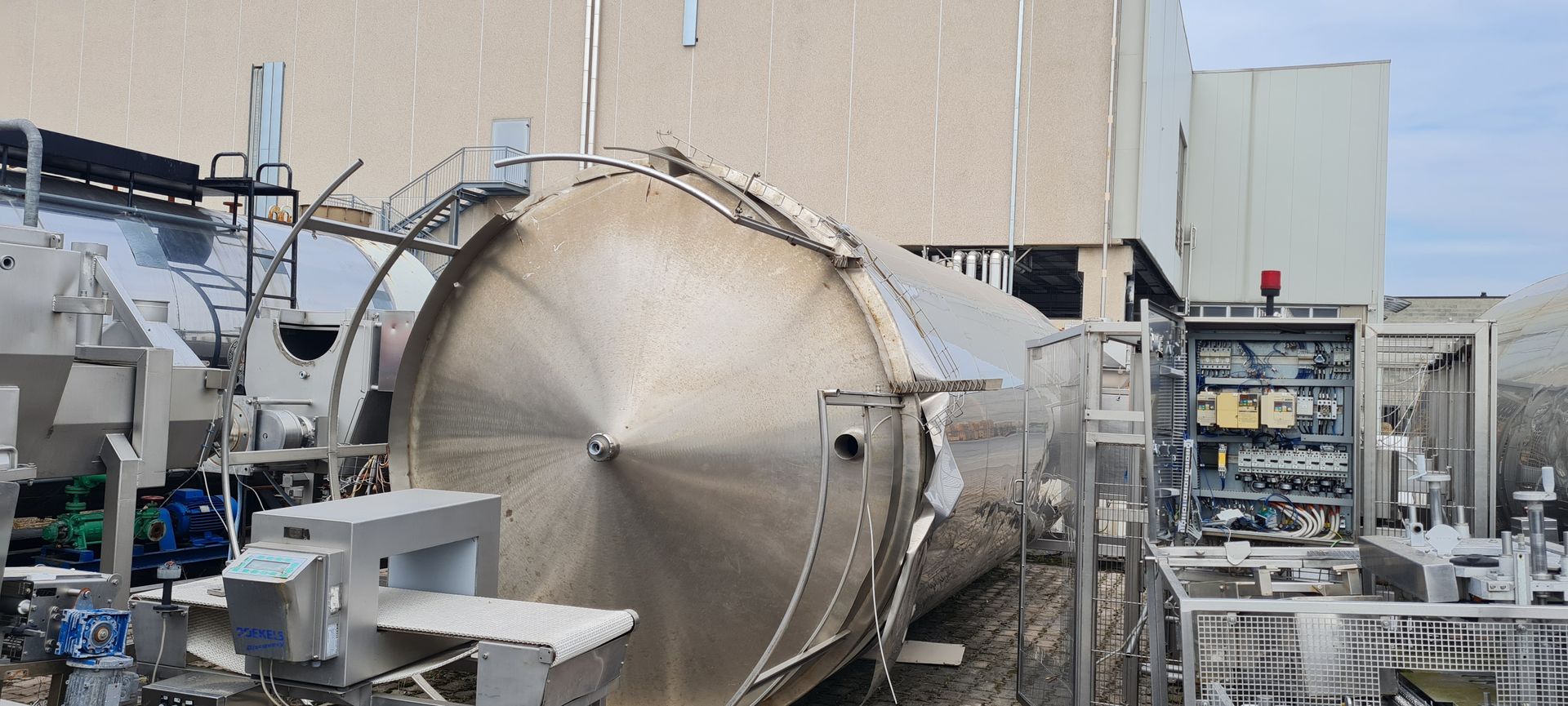 Davanti a un edificio si trova un grande serbatoio di acciaio inossidabile.