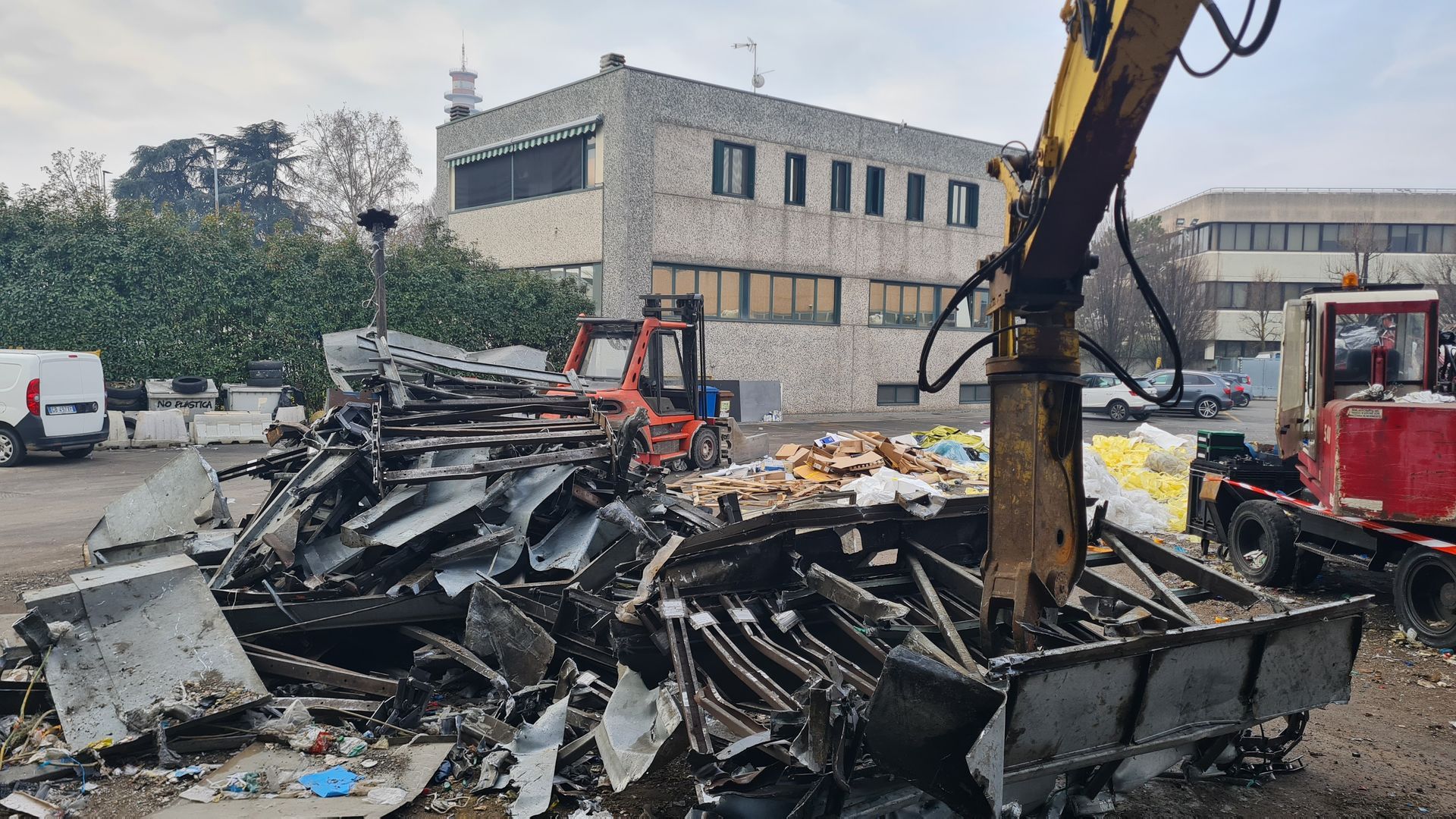 Davanti a un grande edificio c'è un grosso mucchio di rottami metallici.