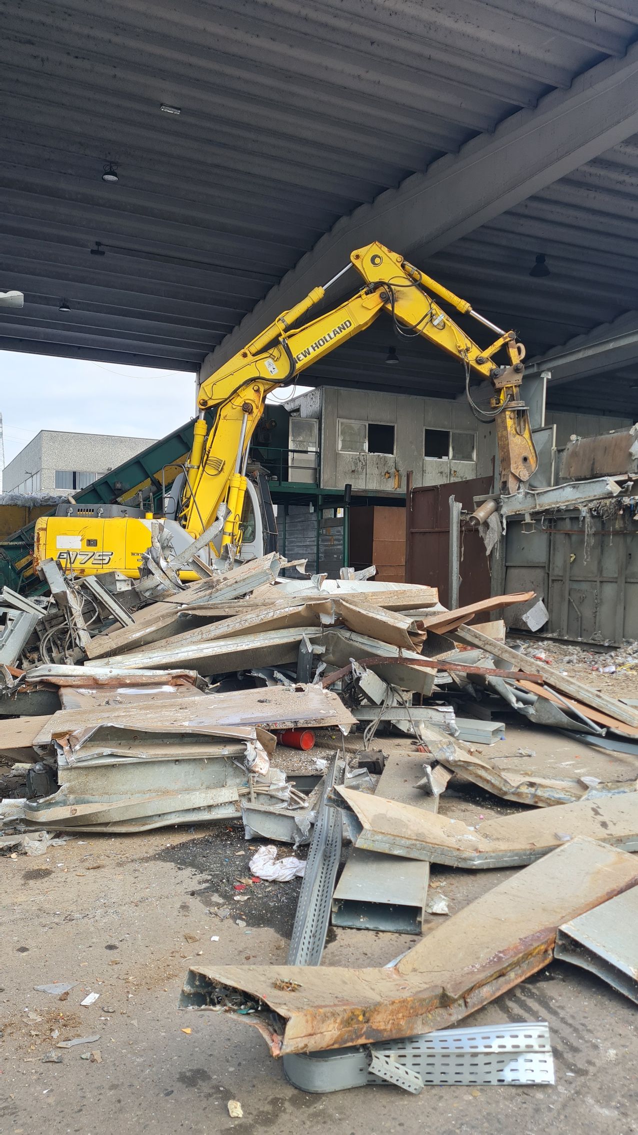 Un grande escavatore giallo sta demolendo un edificio.