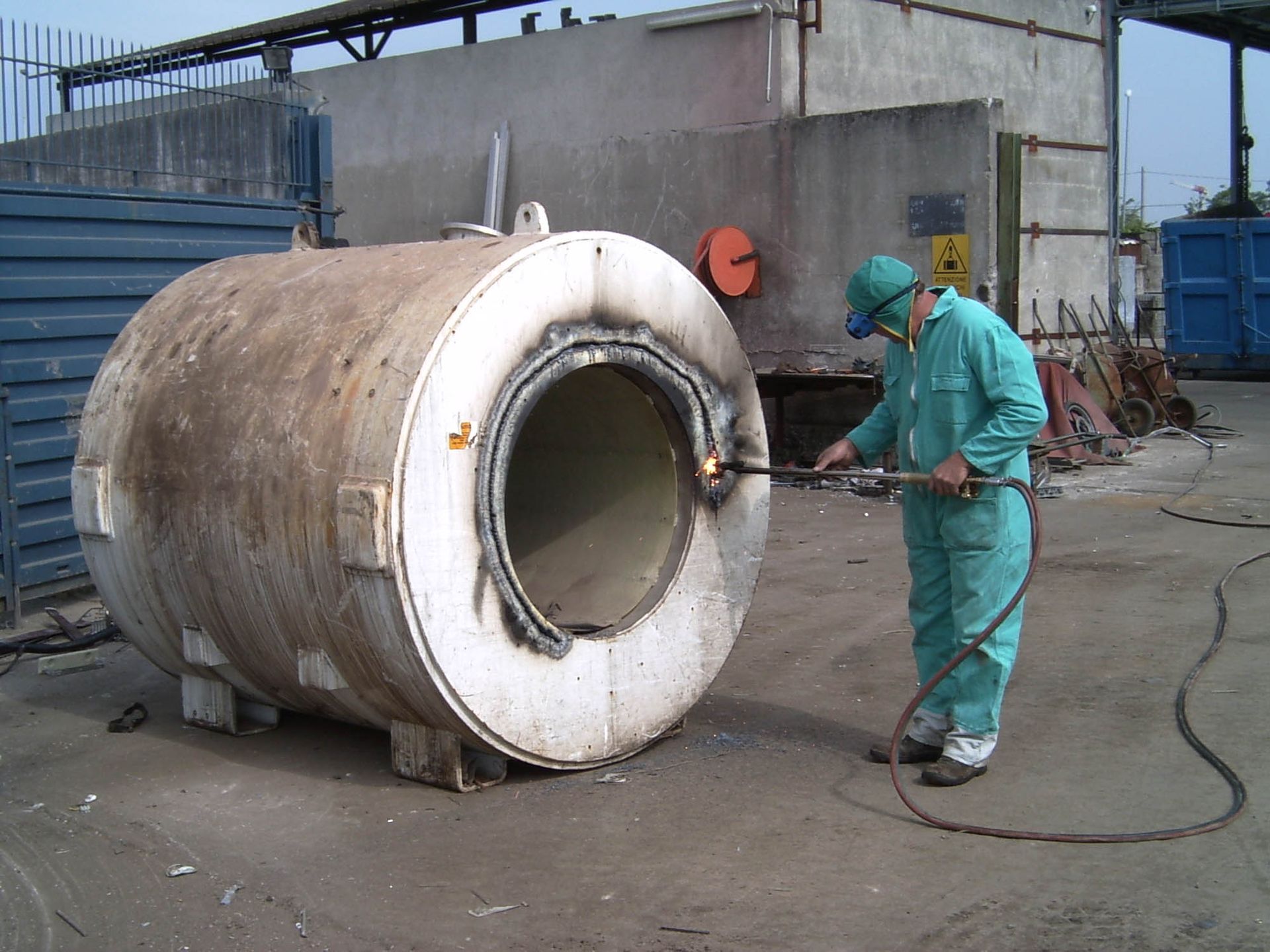 Un uomo con una tuta verde sta saldando un grosso tubo