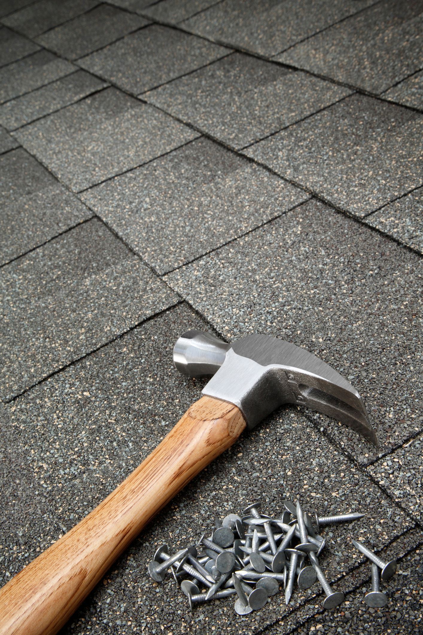 A hammer and nails are laying on a roof.