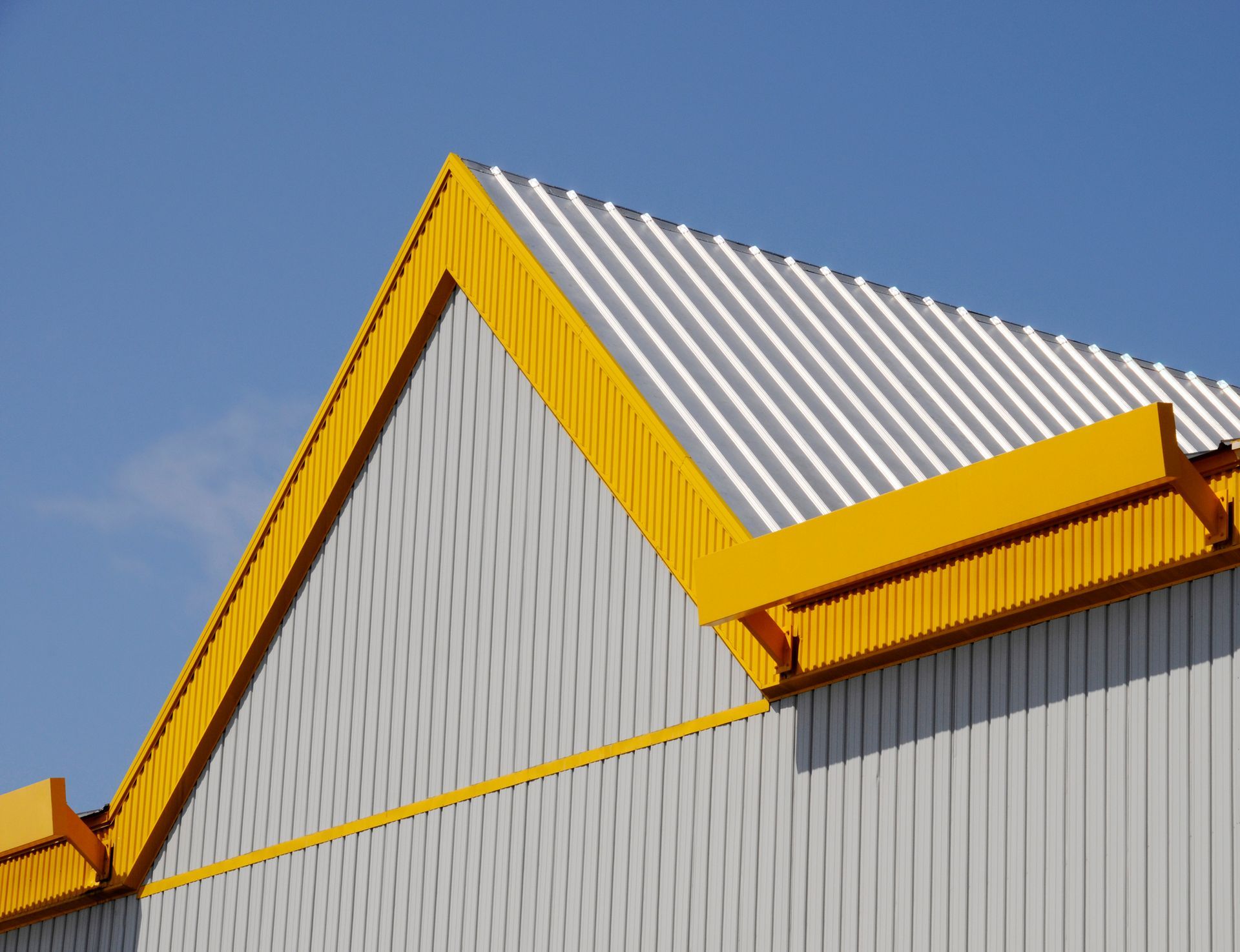 A white building with a yellow roof and a blue sky in the background