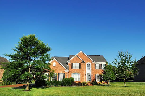 A large brick house with a lush green lawn in front of it.